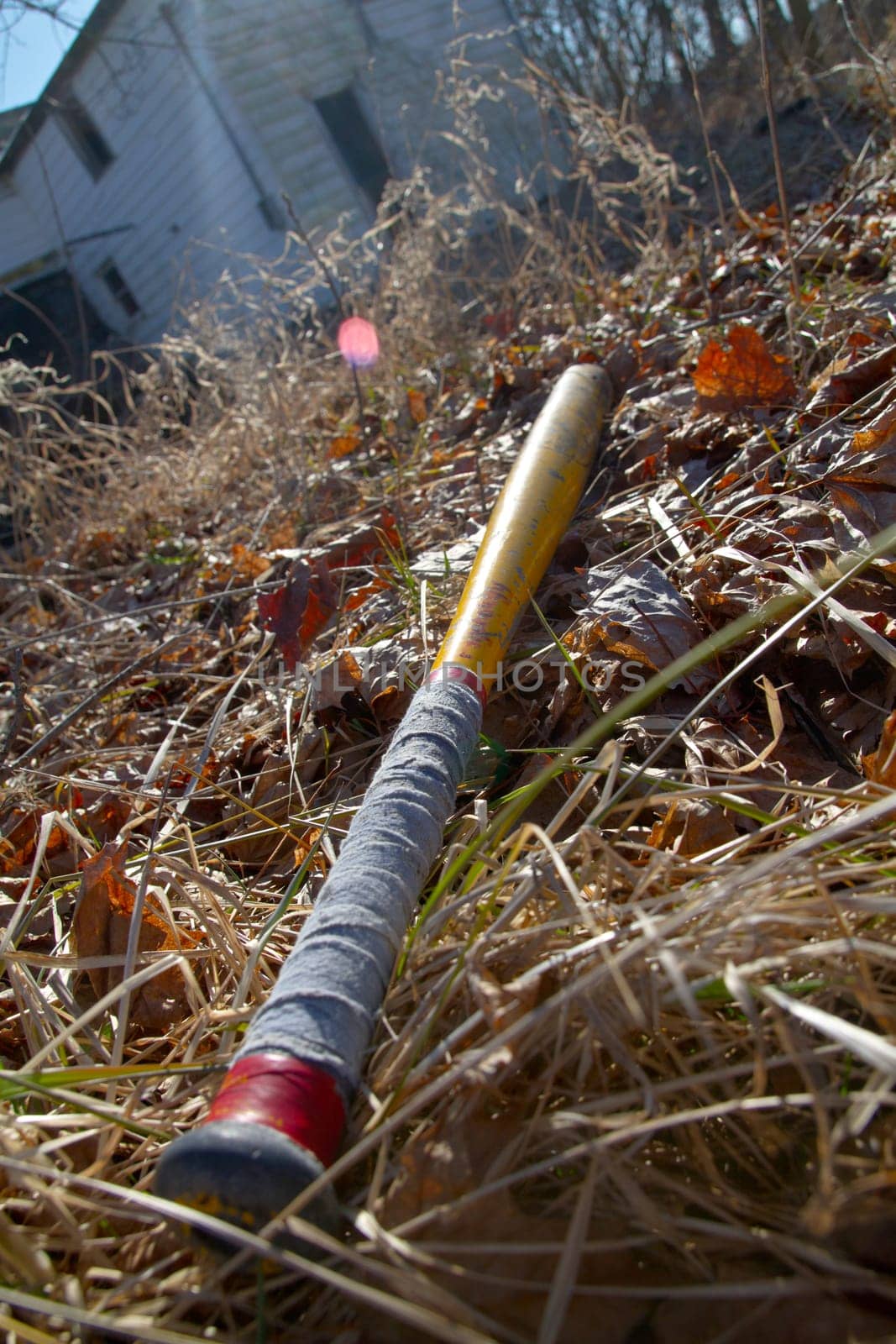 Vintage Baseball Bat on Autumn Field with Abandoned Building Background by njproductions