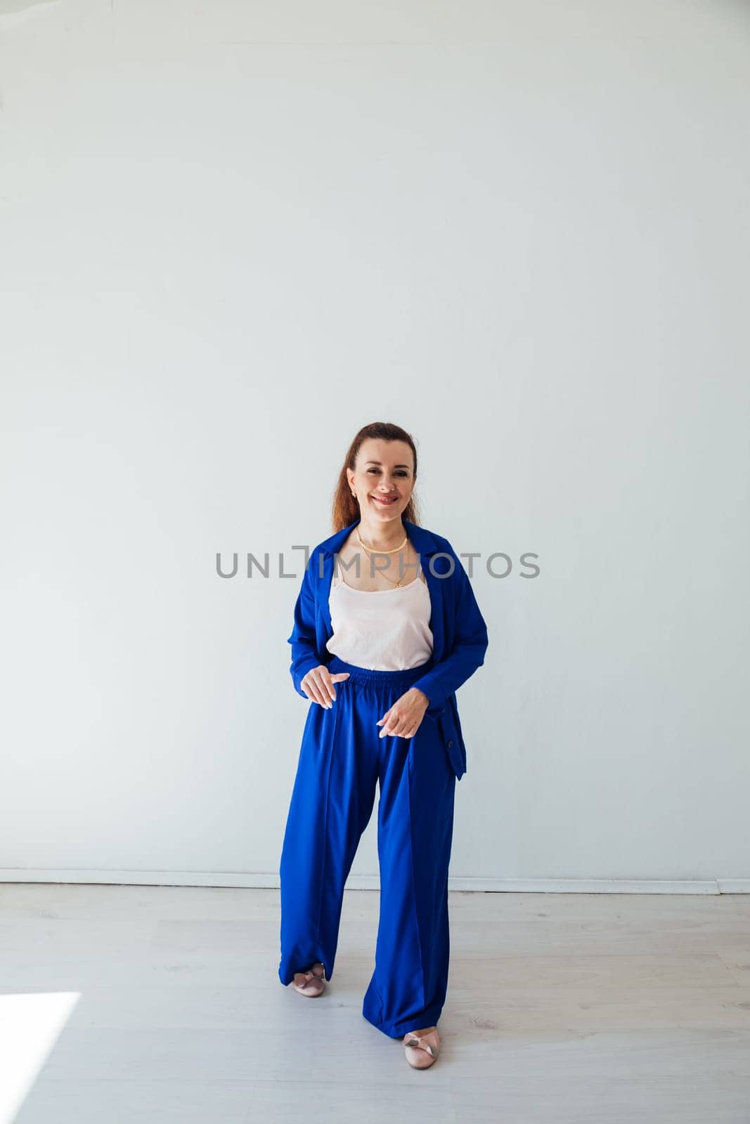 Beautiful brunette woman in blue summer suit posing in white room