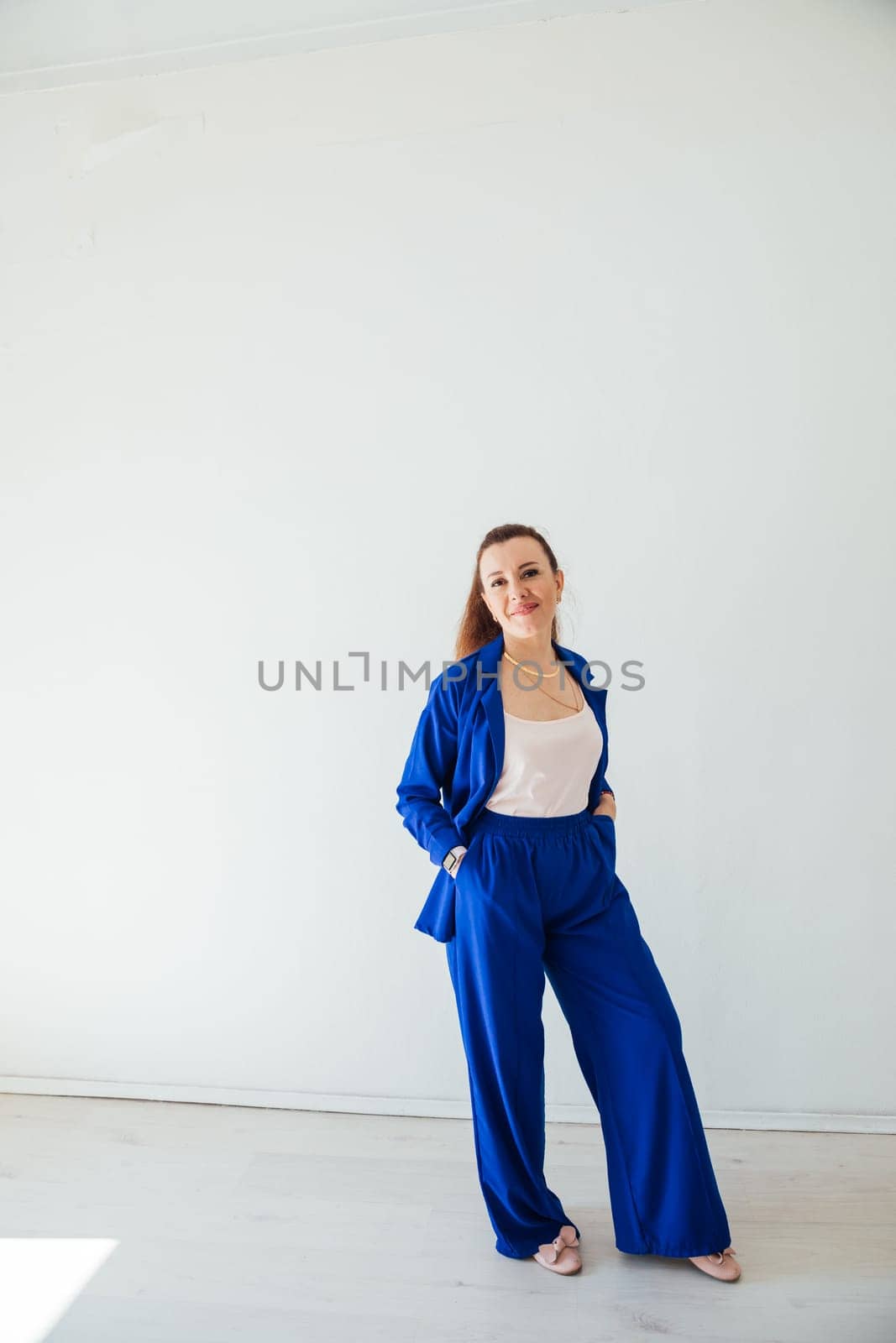 Beautiful brunette woman in blue summer suit posing in white room