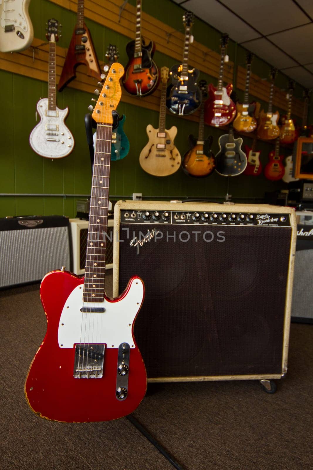 Red Electric Guitar Display in Music Store with Vintage Amplifier by njproductions