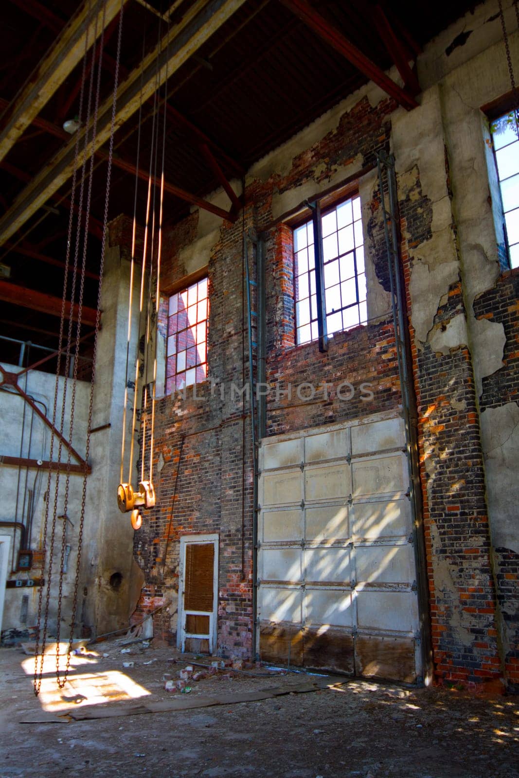 Abandoned Industrial Warehouse Interior with Deteriorating Brickwork and Hand Chain Hoist by njproductions