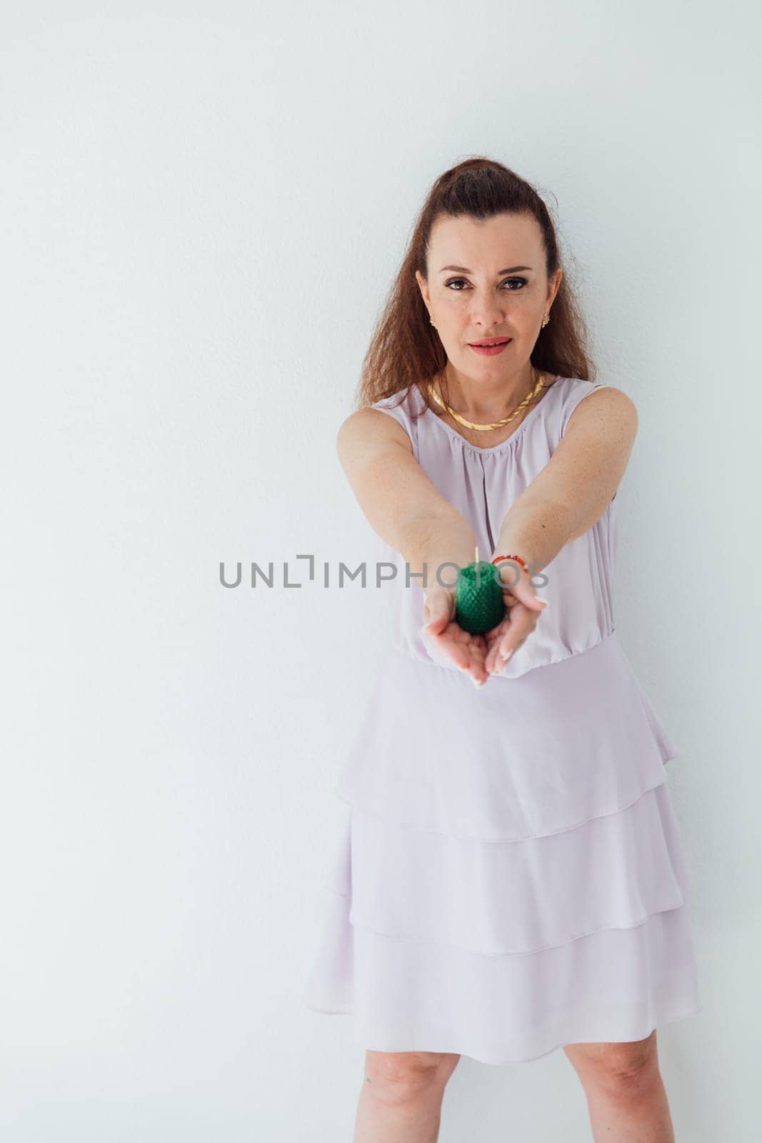 Brunette woman holding a green candle in her hands by Simakov