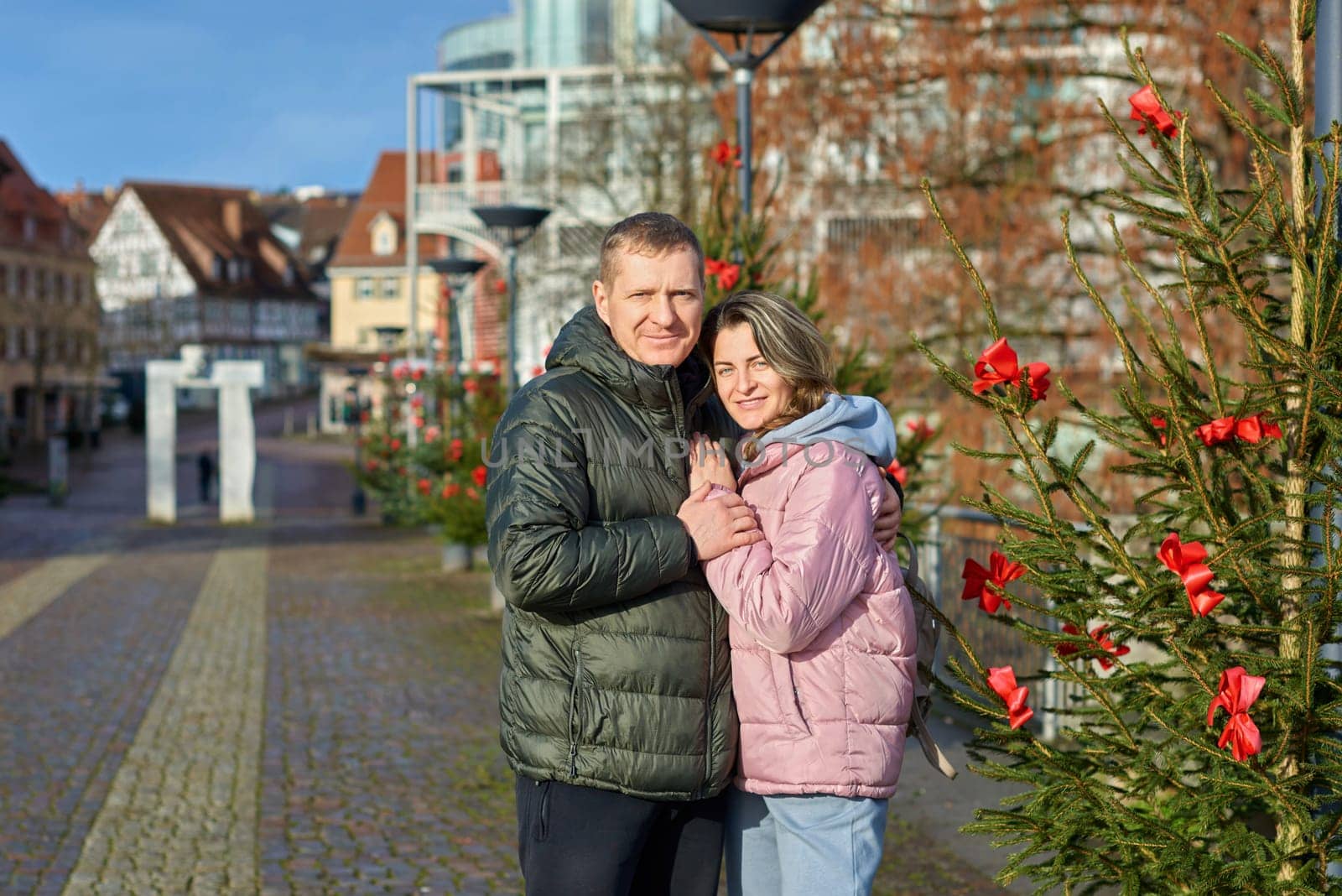 couple in love A guy and a girl hugging on the street of the old European town of Bietigheim-Bissingen in Germany on Christmas Eve. The city streets are decorated with Christmas trees and New Year's decorations. Capturing Love in the Glow: Couple Embracing in the Enchanting Streets of Bietigheim-Bissingen, Germany, on Christmas Eve by Andrii_Ko