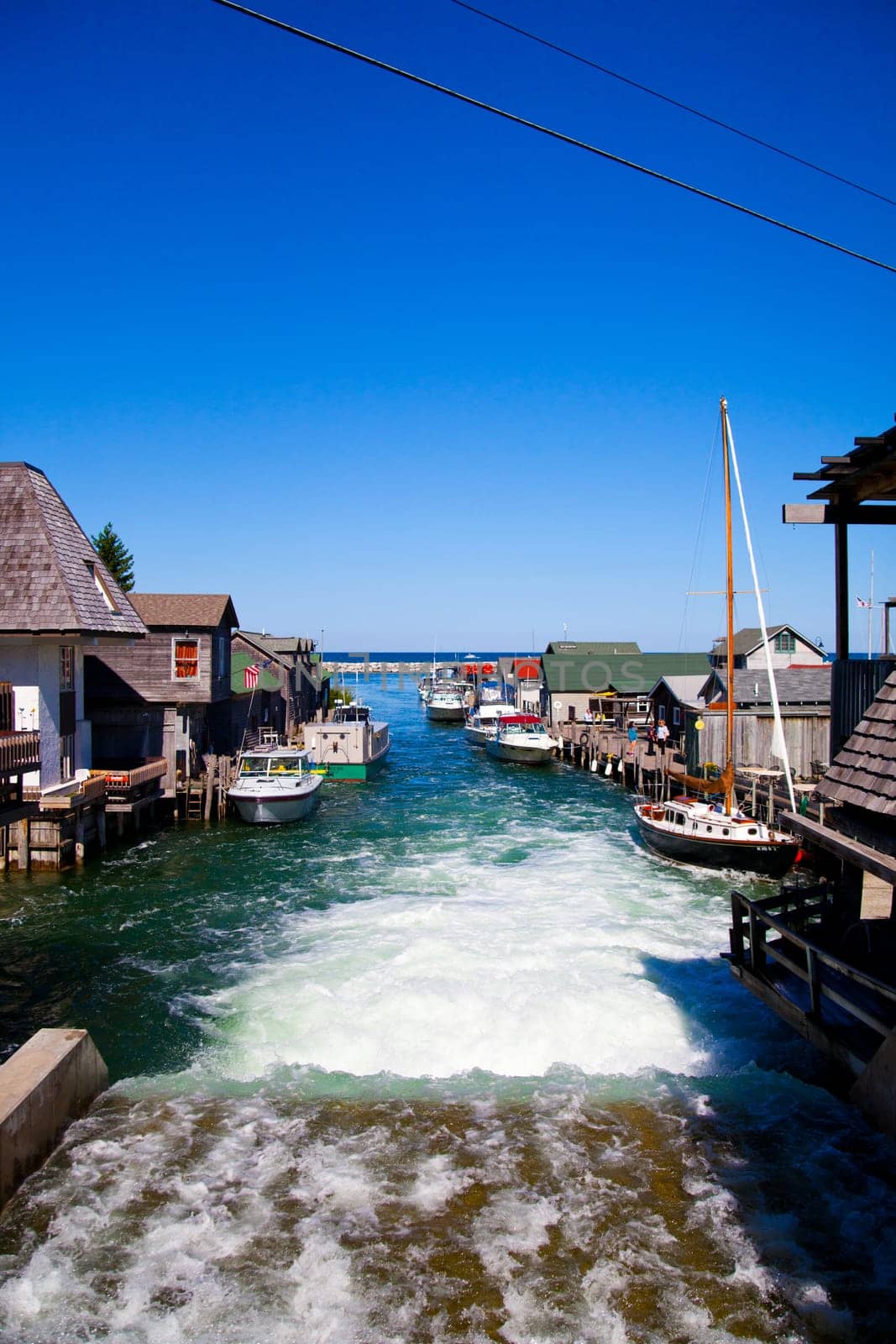 Tranquil coastal scene in Empire, Michigan showcasing picturesque waterfront with rustic boathouses and docked boats under clear blue skies.