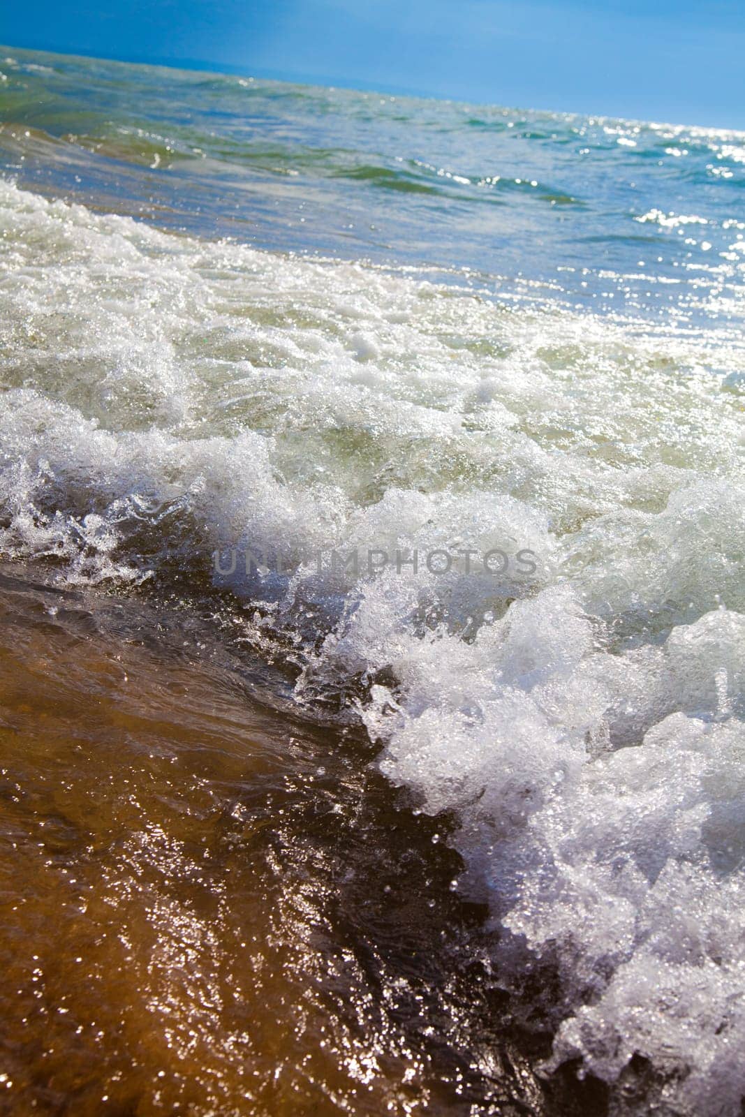 Experience the raw power and tranquil beauty of Lake Michigan's crashing waves on a sunny day at the beach - a perfect summer getaway.