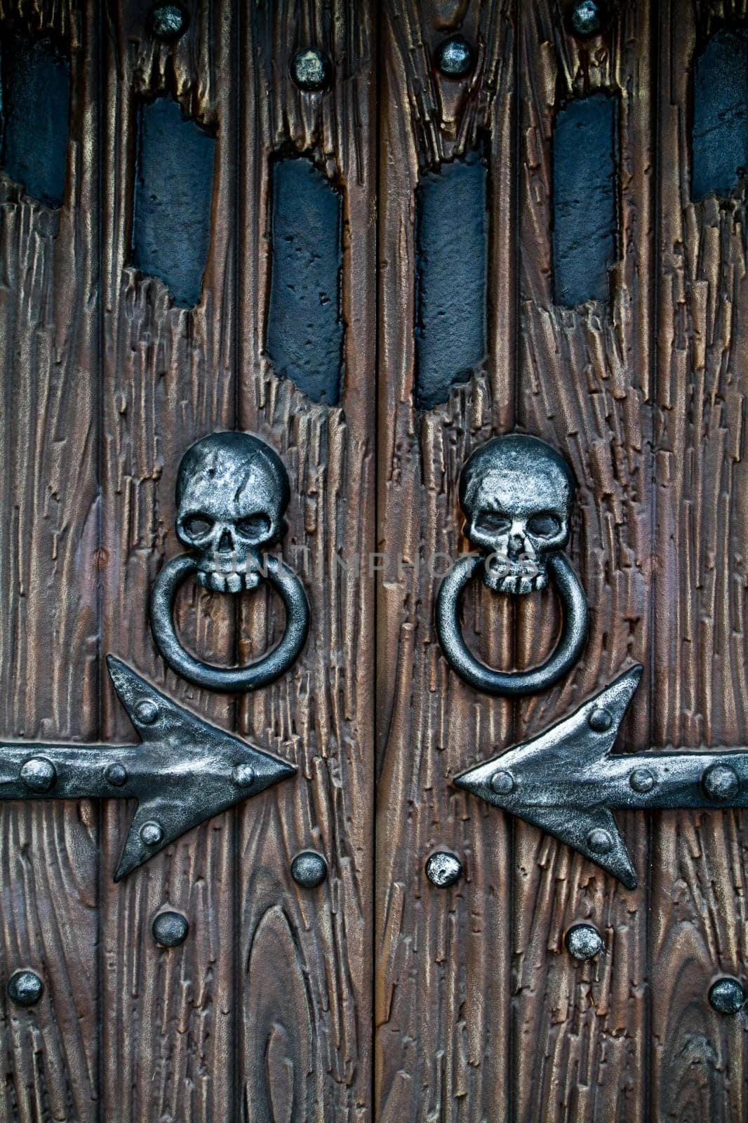 Enigmatic and Gothic wooden door adorned with two realistic metal skull knockers, showcasing intricate craftsmanship and historical charm. Perfect for Halloween, fantasy, or historical-themed projects. Located in Gatlinburg, Pigeon Forge.