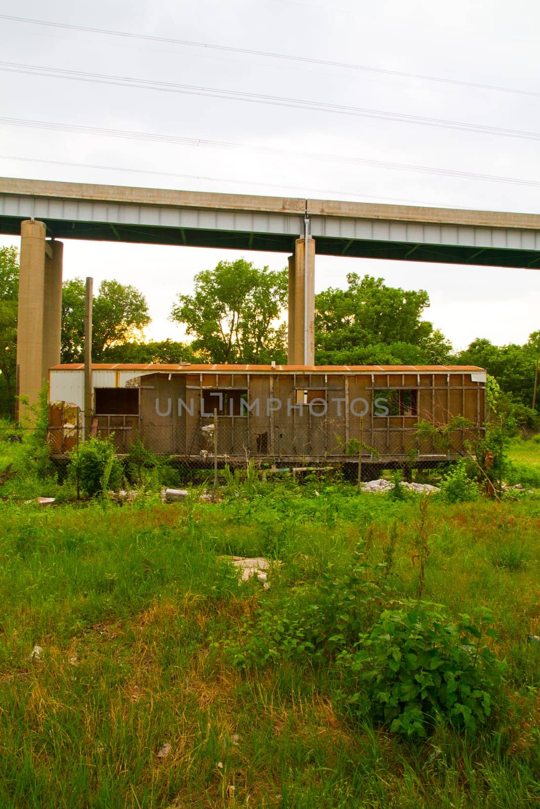 Desolate Urban Decay: Abandoned building overgrown with foliage in East St. Louis, Illinois, stands in stark contrast to a towering concrete bridge. Symbolizing the passage of time and the clash between nature and infrastructure.