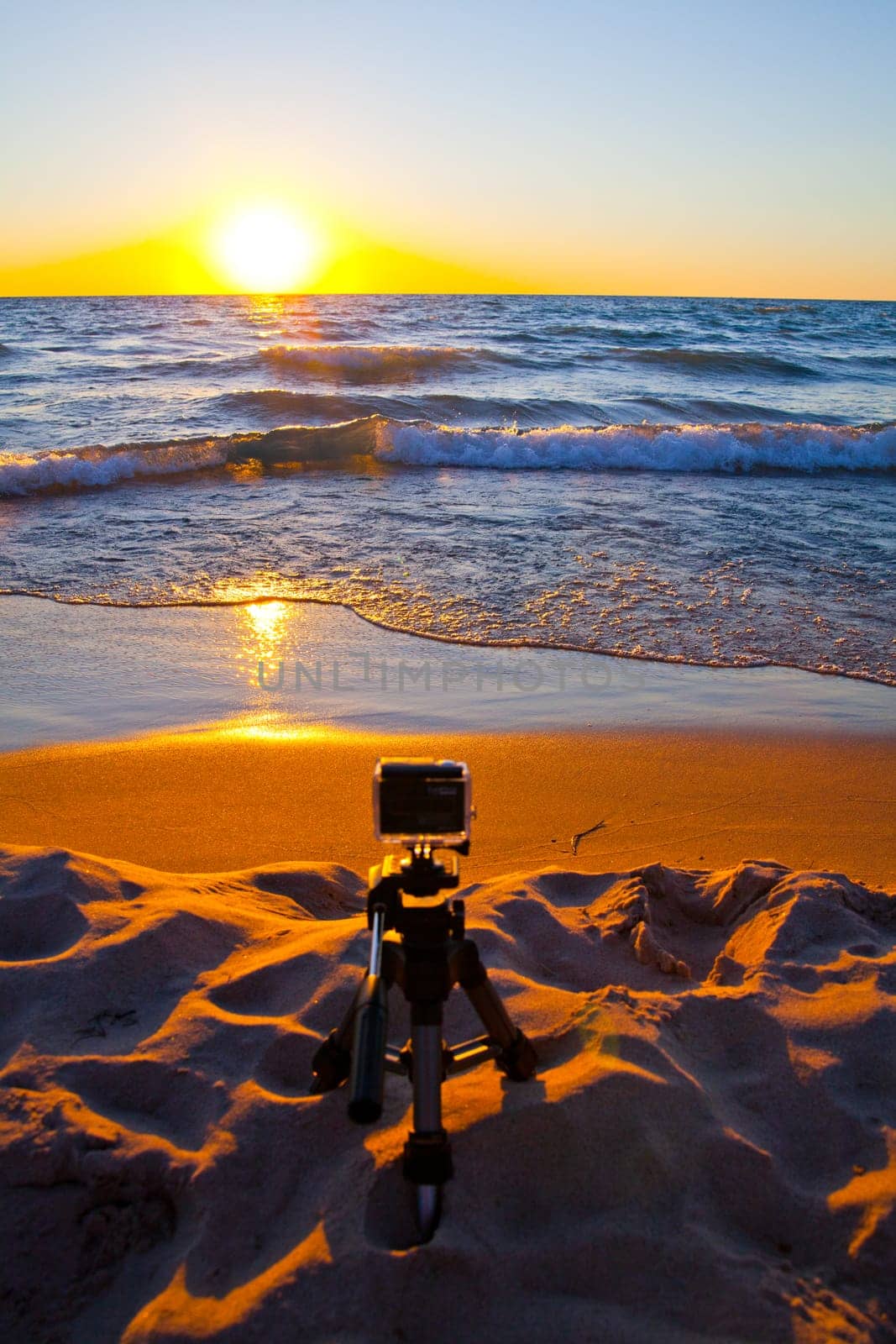 Capture the beauty of a beach sunset with this camera set against the golden hues of the horizon. Perfect for photography, travel, and technology themes.