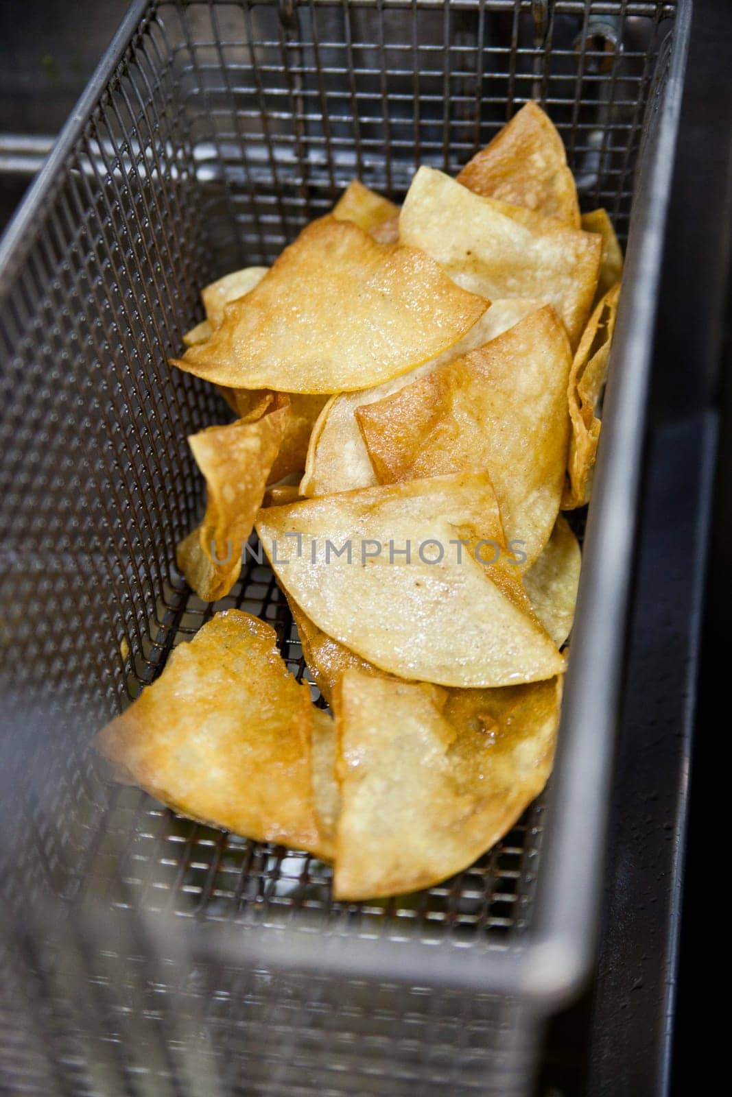Close-Up of Freshly Fried Golden Tortilla Chips in Metal Basket by njproductions
