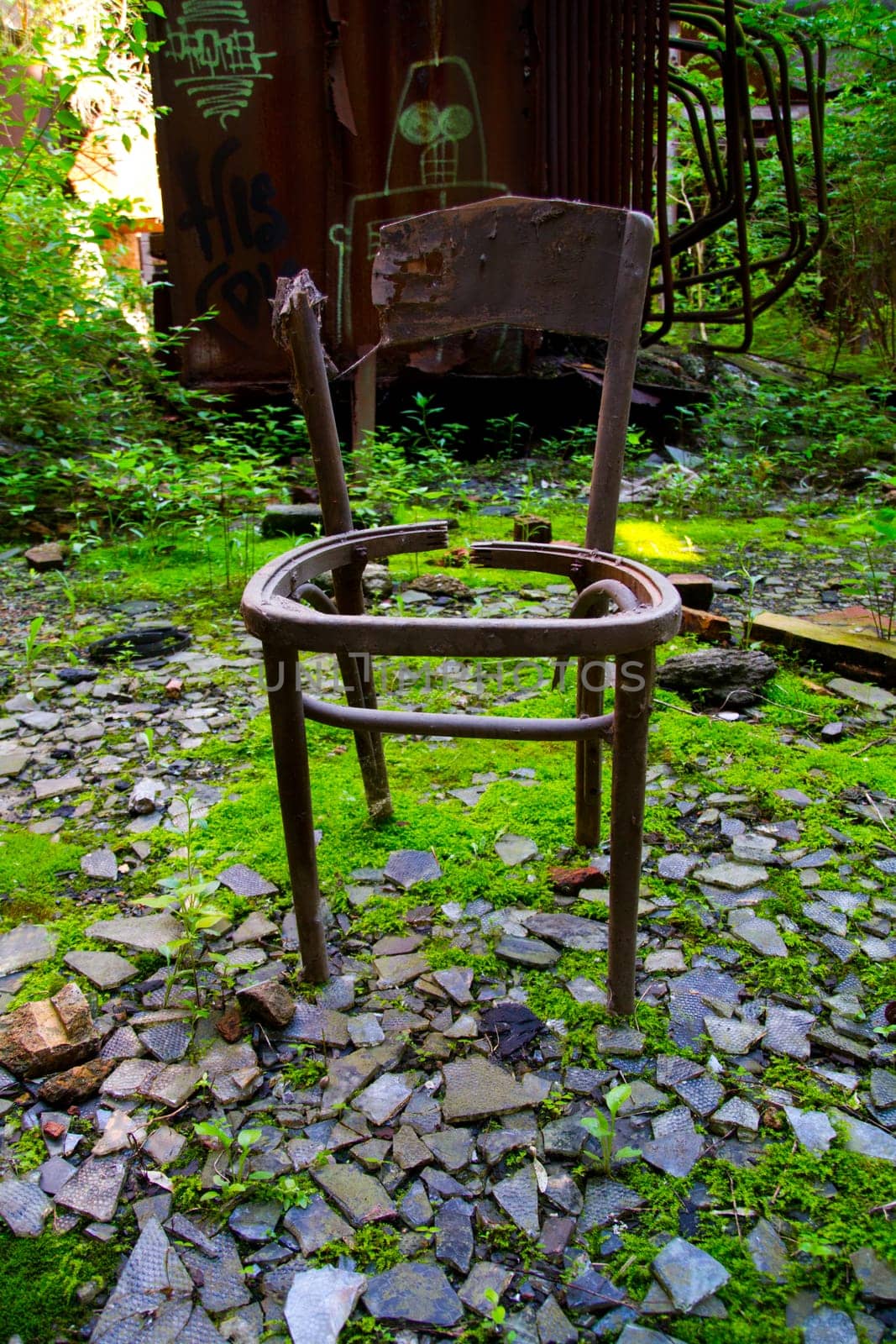 Nature's Resurgence: A weathered chair stands amidst urban decay, symbolizing neglect and desolation. Vibrant green moss engulfs broken tiles and debris, while a graffiti-tagged train car adds to the forgotten.