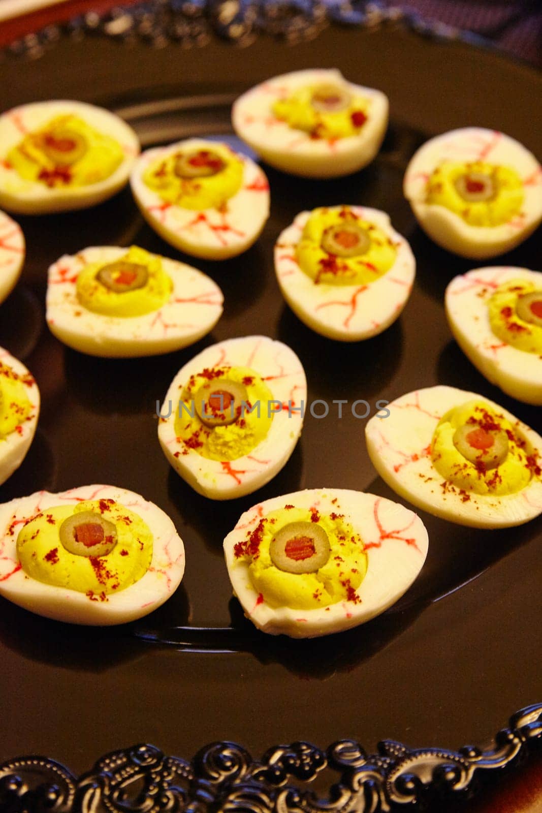 Creepy blood eye deviled eggs with a vibrant twist, elegantly presented on an ornate plate. Perfect for upscale dining, catering events, or festive celebrations.