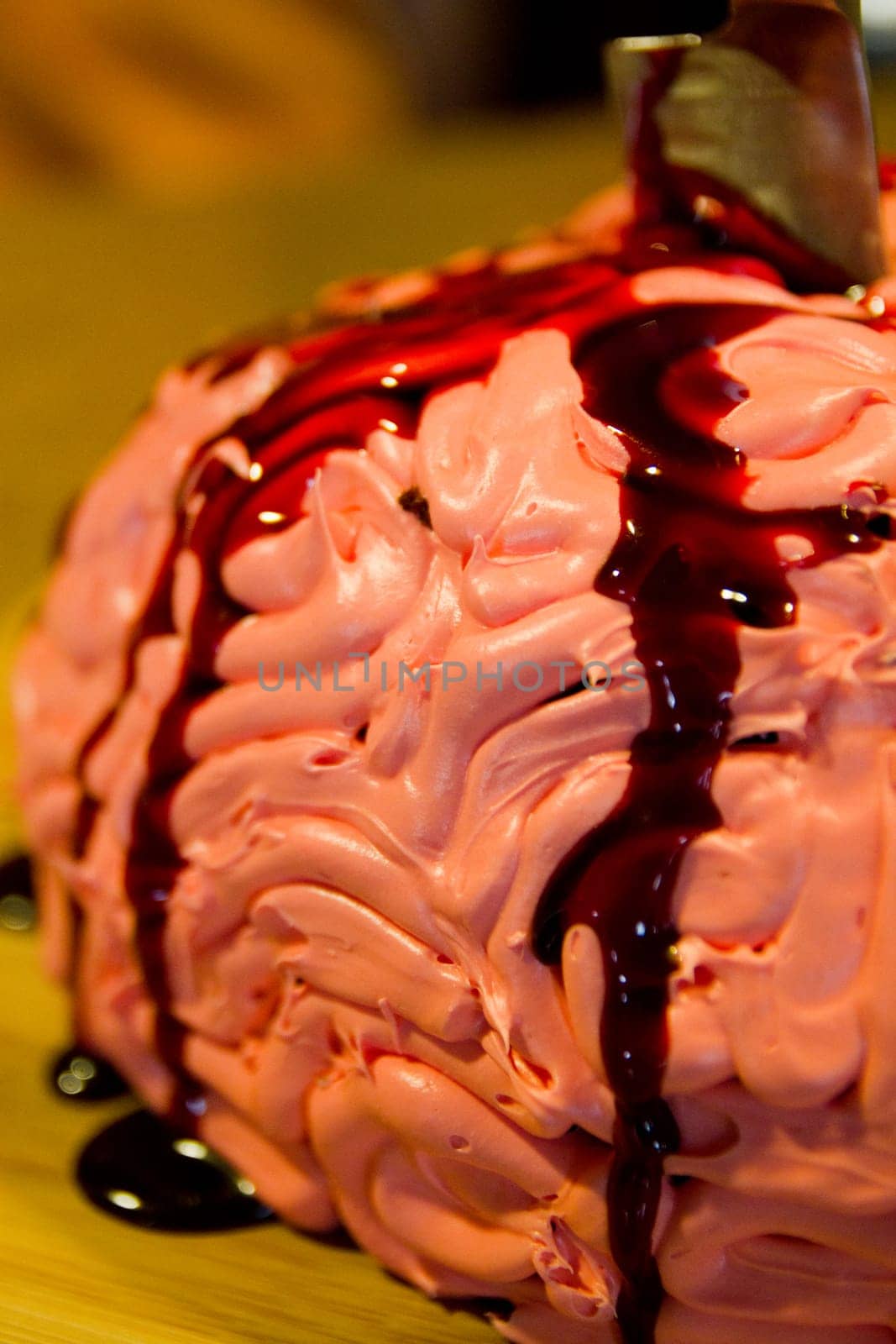 Delectably creep Halloween Brain dessert with swirls of pink frosting and a drizzle of 'blood' sauce, capturing the indulgence and art of dessert-making. Perfect for bakeries and culinary blogs seeking to inspire creepy but sweet cravings.