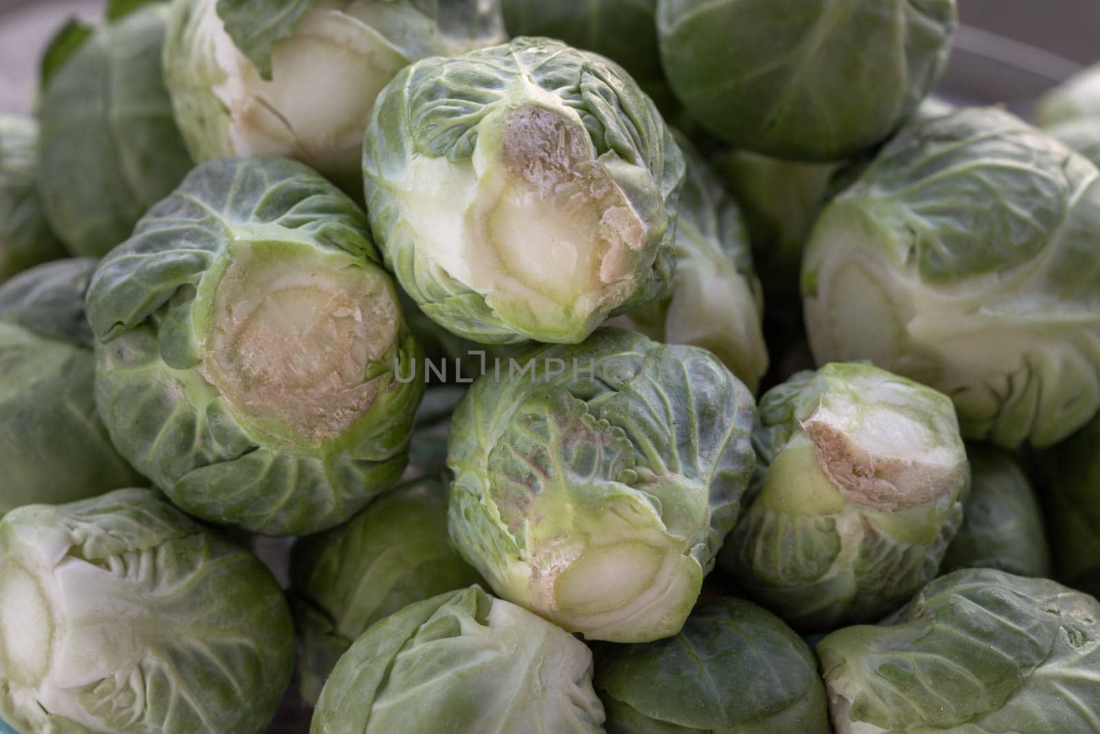 Close-up of Fresh raw organic Green brussel sprouts vegetable on Wooden cutting board with Natural sunlight. Uncooked brussels sprouts, Space for text, Selective focus.