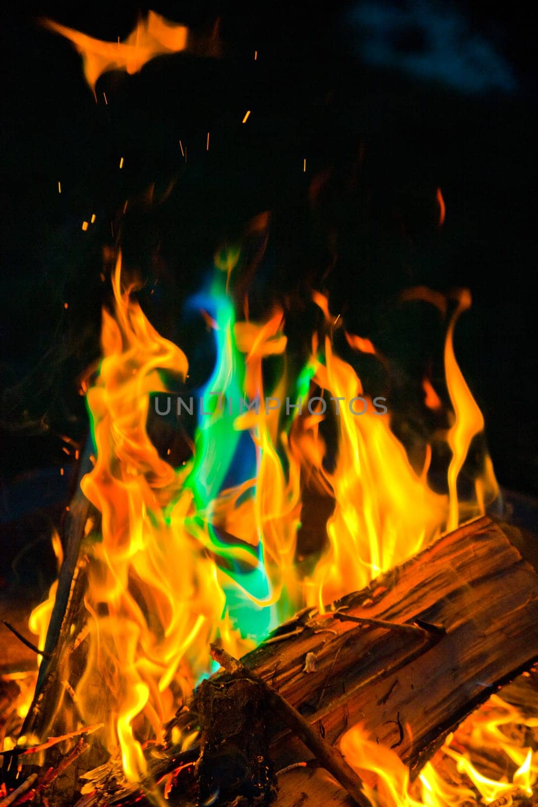 Vibrant Spectrum of Flames in Wood Fire at Night with Blue-Green Flare by njproductions