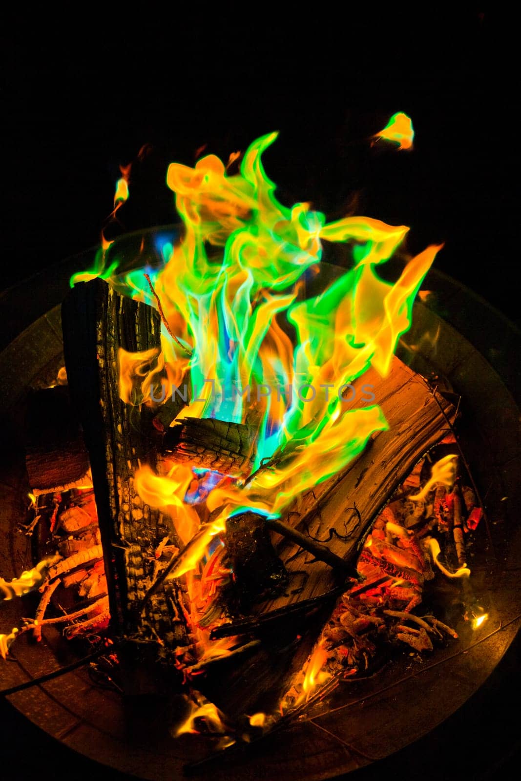 Experience the mesmerizing dance of vibrant, mystique-colored flames in a metal fire pit, illuminating the night in Fort Wayne, Indiana.