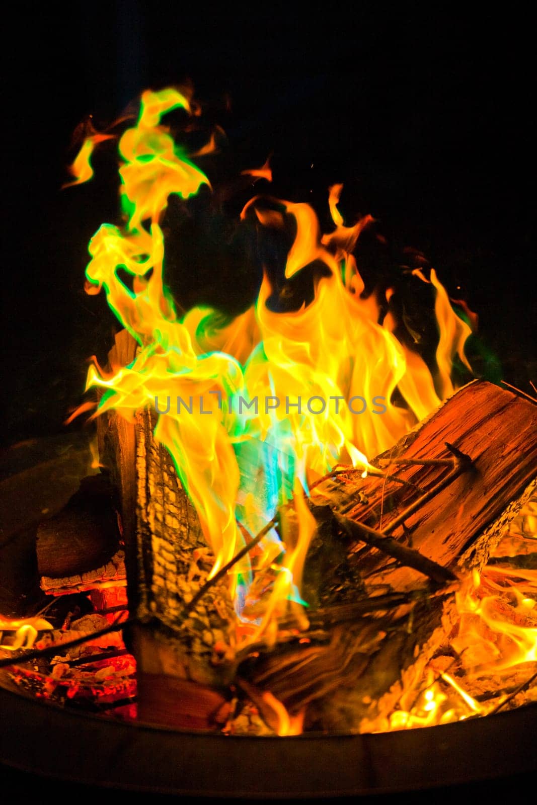 Captivating and Mystical: Experience the mesmerizing dance of vibrant flames in an outdoor fire pit in Fort Wayne, Indiana. The intense orange core radiates warmth and energy, while the flickering green flames add an unusual and mystical touch.