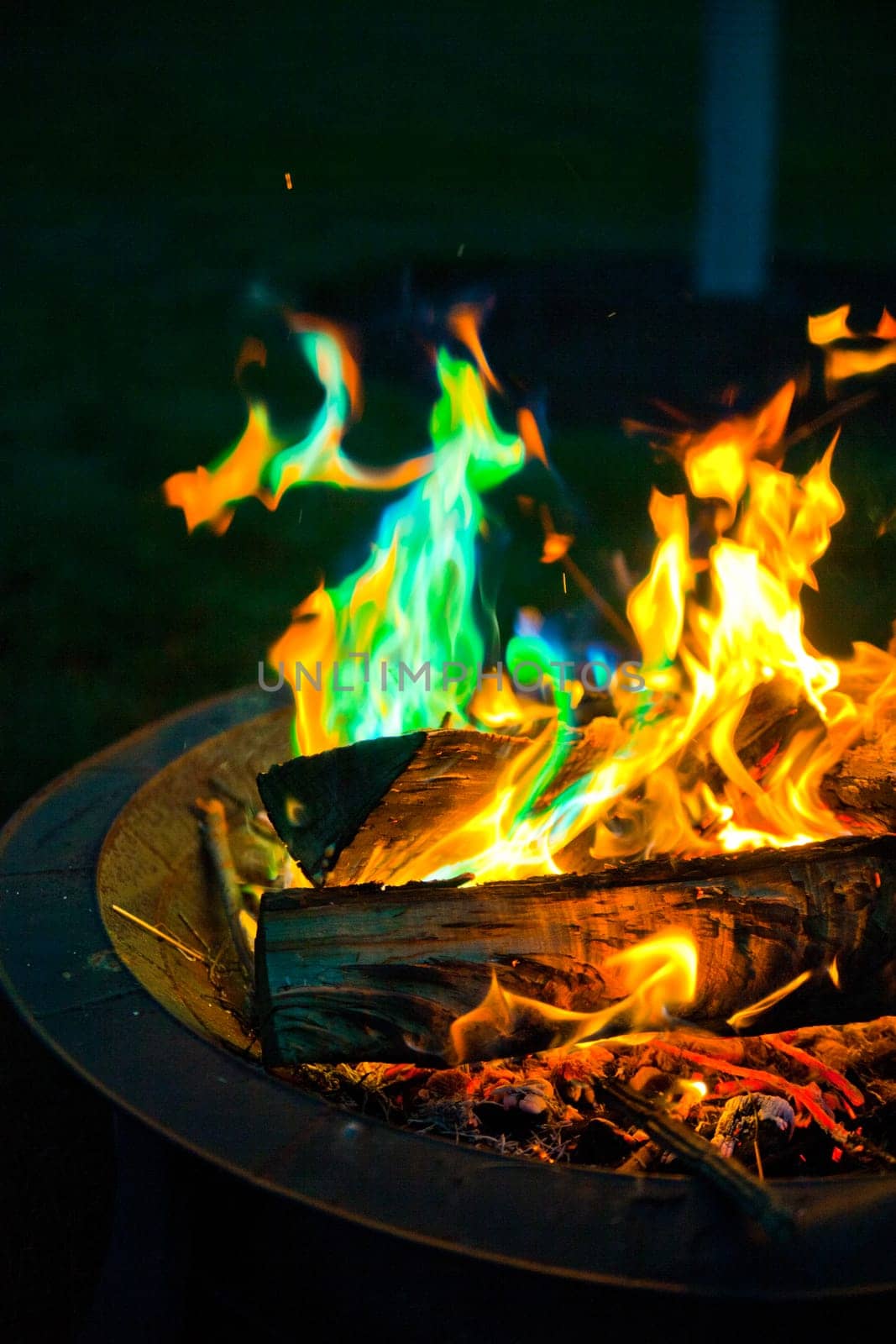 Experience the captivating magic of a vibrant campfire with green flames. The mesmerizing dance of colorful flames adds a touch of enchantment to outdoor gatherings and camping adventures. Safe and controlled within a metal fire pit.