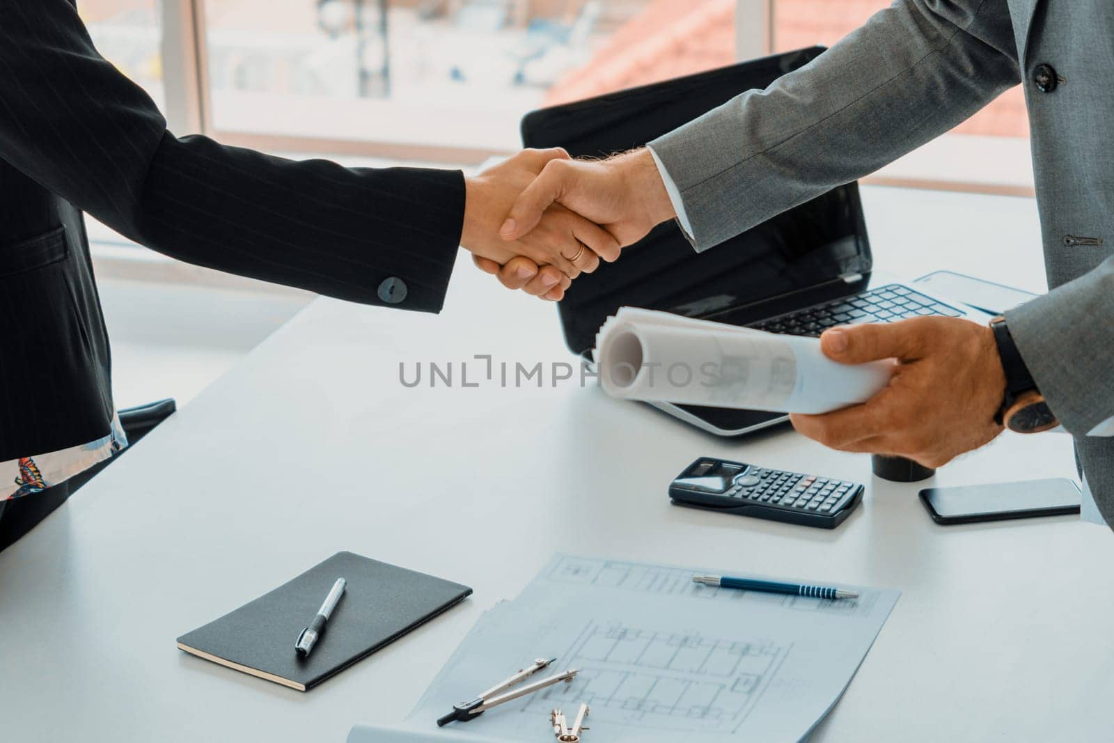 Businessman handshake businesswoman in office. uds by biancoblue