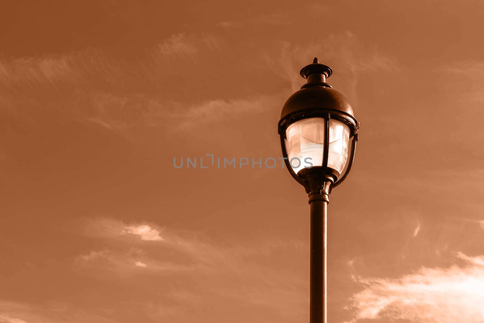 Public street lighting pole with LED lights with an amazing sunset color background. Image toned in Peach Fuzz color of the year 2024