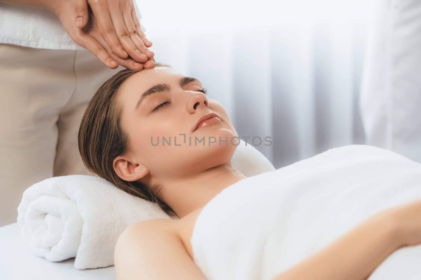 Caucasian woman enjoying relaxing anti-stress head massage and pampering facial beauty skin recreation leisure in dayspa modern light ambient at luxury resort or hotel spa salon. Quiescent