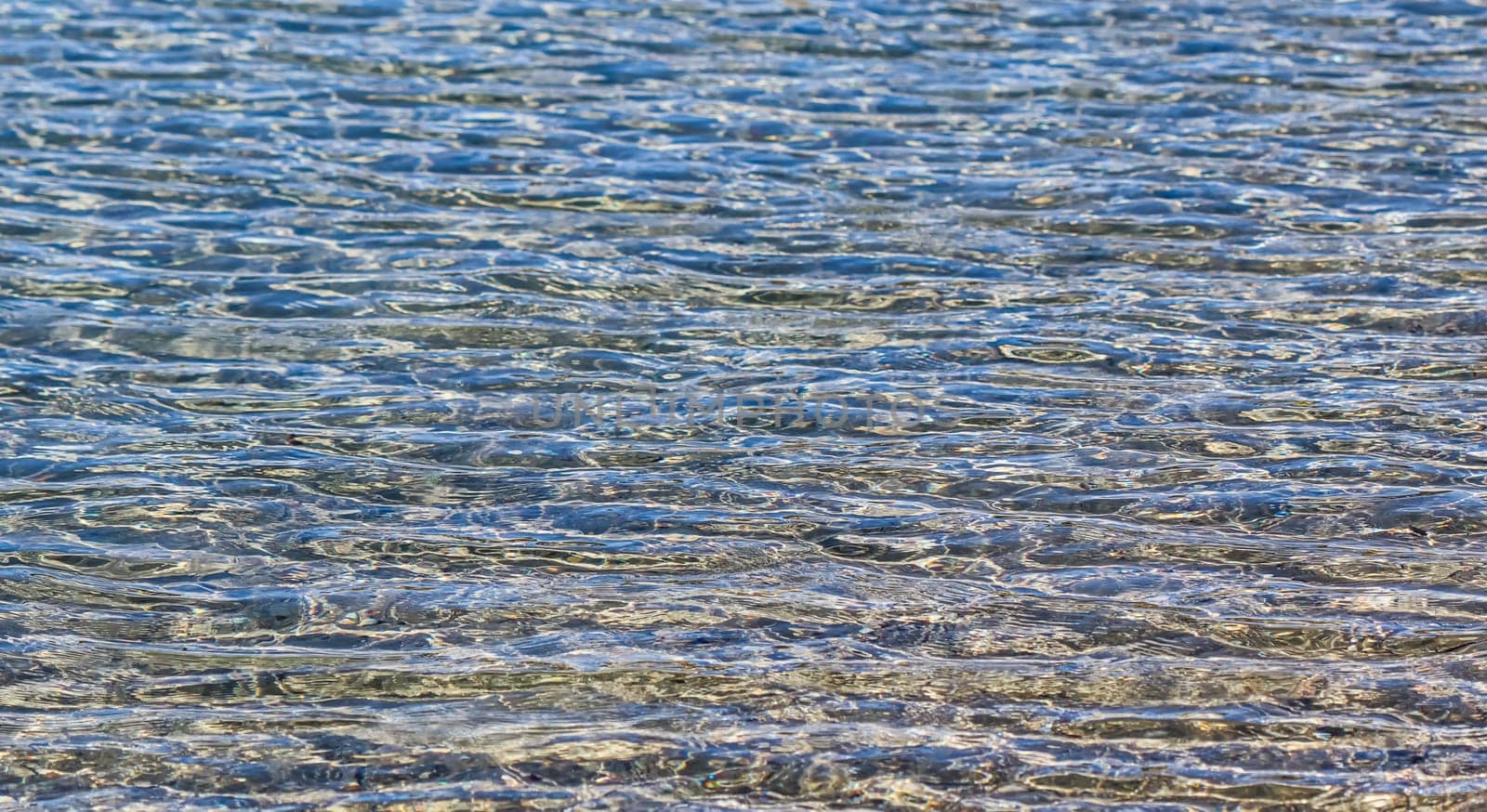 Blue sea in sunshine glow as surface background. Summer holidays and coastal nature concept