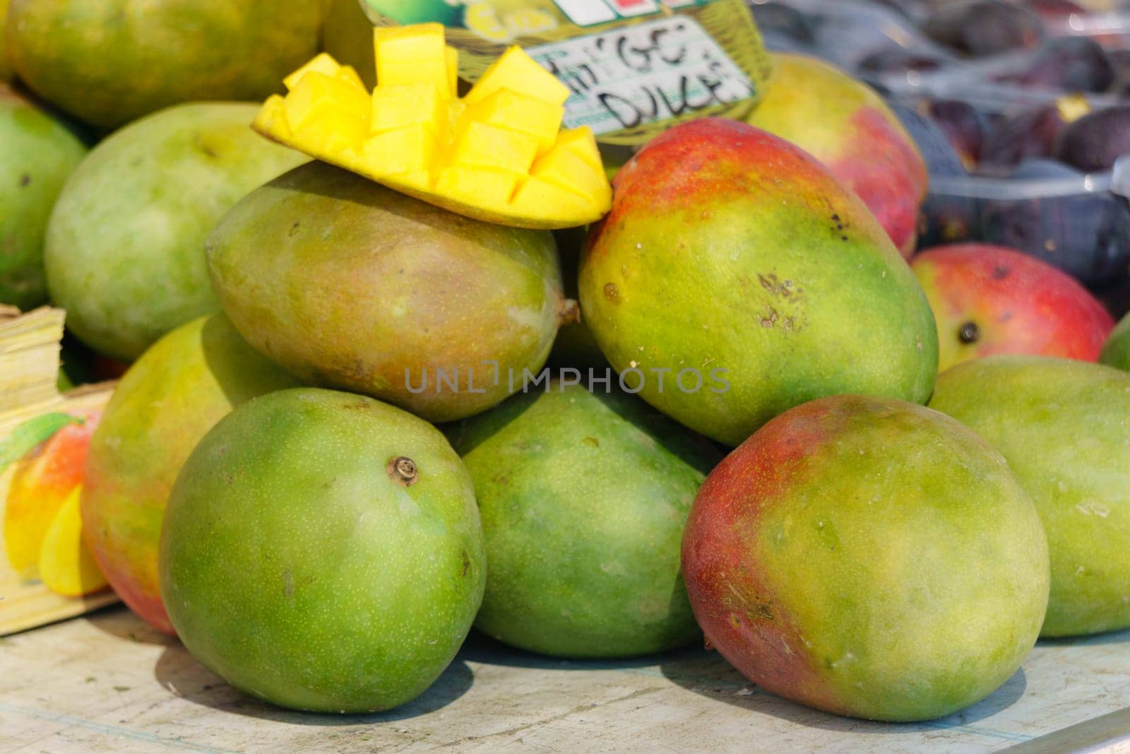 pile of mangoes, whole and cut, on a table in a street market