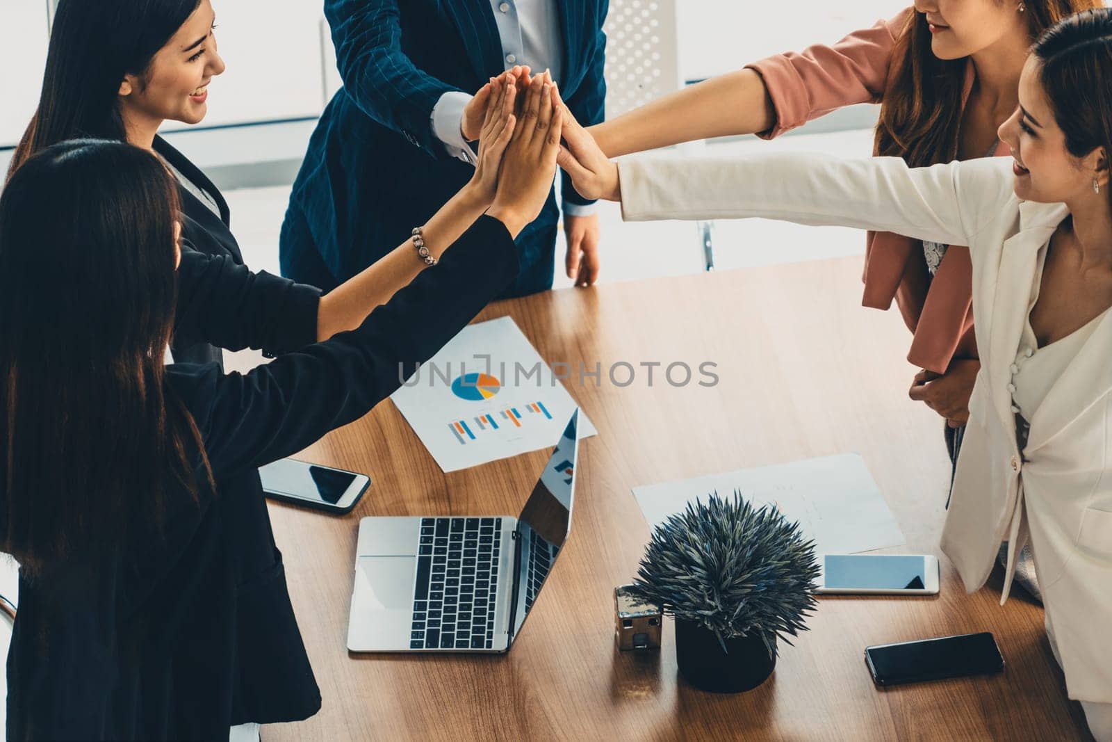 Businesswomen joining hands in group meeting at modern office room showing teamwork, support and unity in work and business. Female power and femininity concept. uds