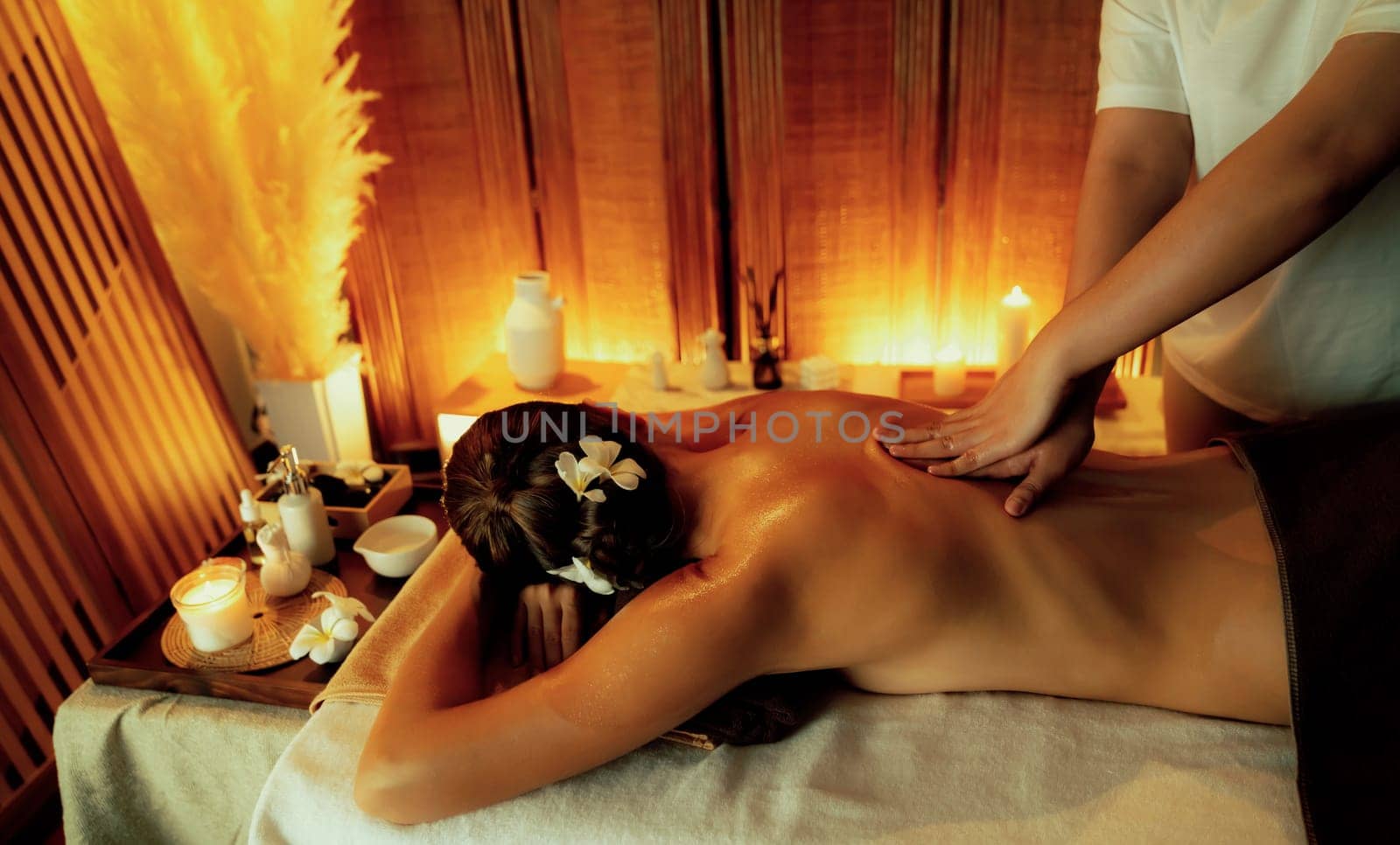 Caucasian woman customer enjoying relaxing anti-stress spa massage and pampering with beauty skin recreation leisure in warm candle lighting ambient salon spa at luxury resort or hotel. Quiescent