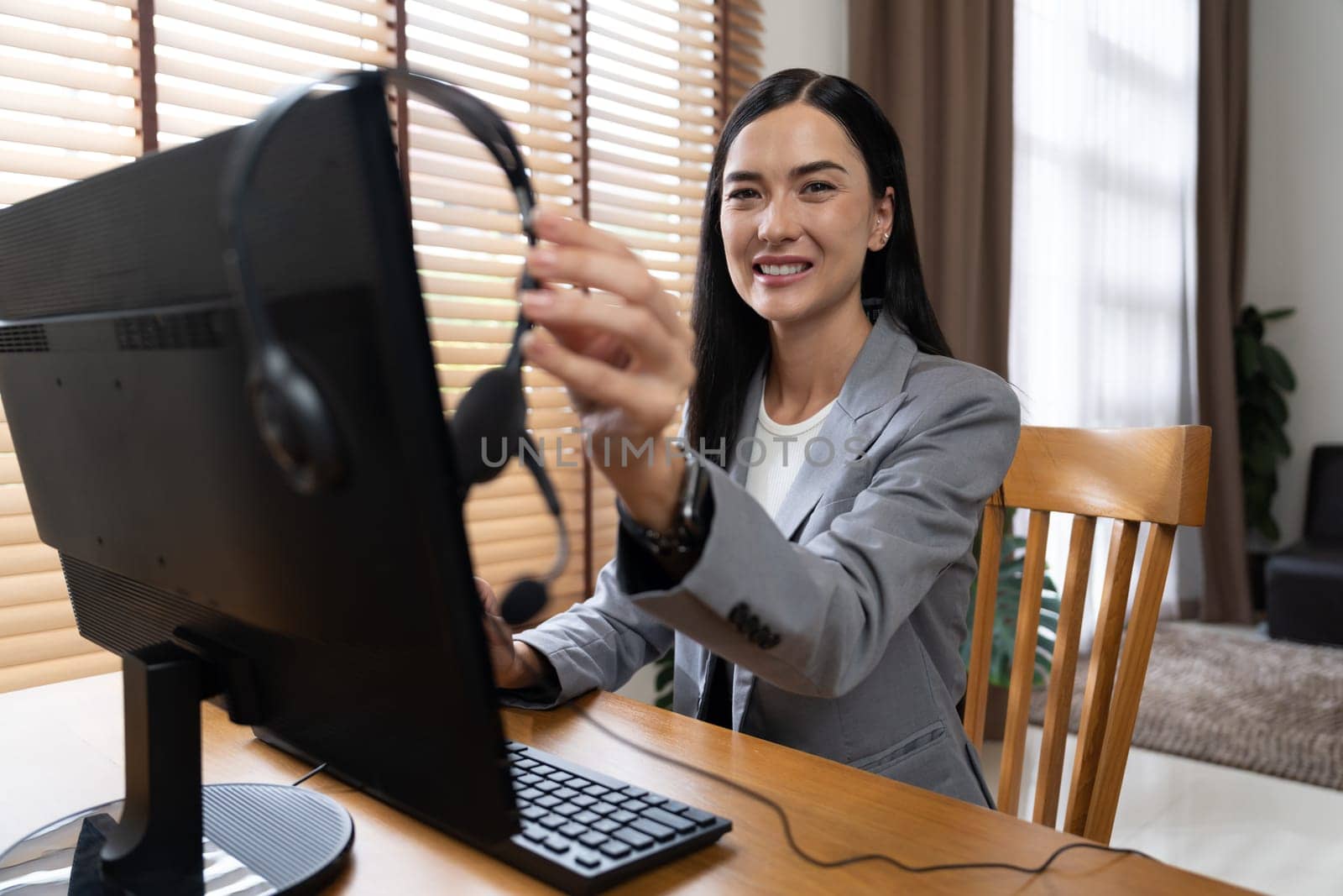 Female call center operator or customer service helpdesk staff working on workspace while talking on the headset to provide assistance for customer. Professional modern business service. Blithe