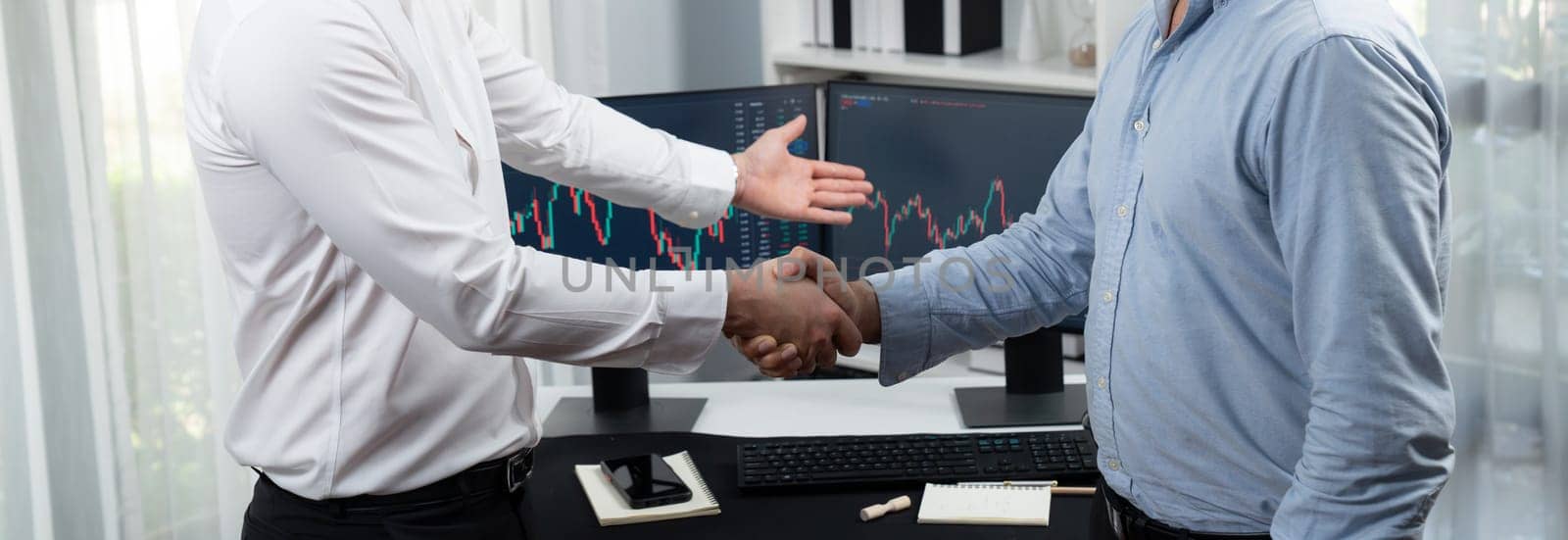 Businessman in stock traders checking hands for successful high profit investment on panorama view. Concept of dealing with each others in technology market on dynamic graph background. Sellable.