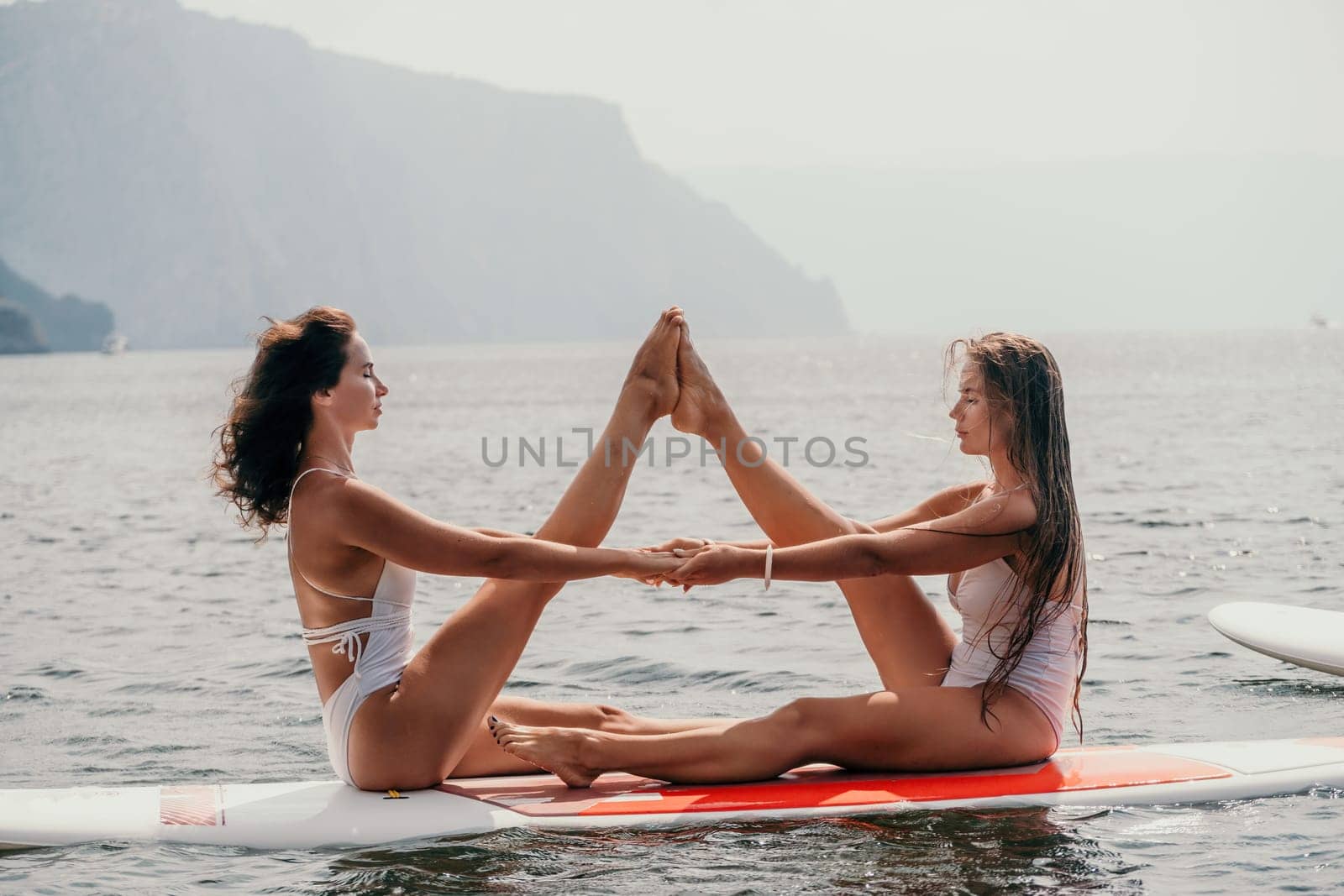 Woman sup yoga. Middle age sporty woman practising yoga pilates on paddle sup surfboard. Female stretching doing workout on sea water. Modern individual hipster outdoor summer sport activity