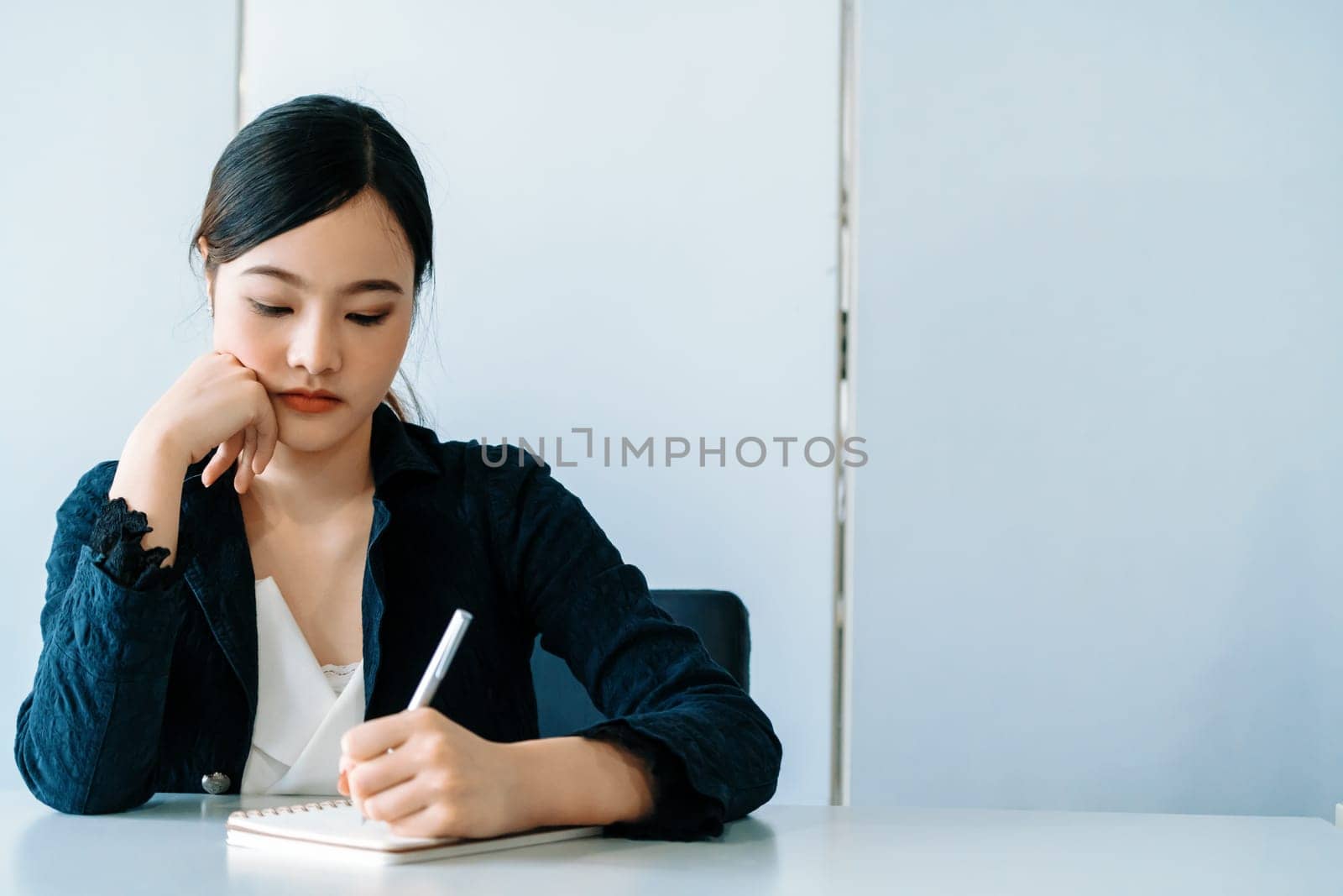 Beautiful young Asian woman writes on notebook. uds by biancoblue