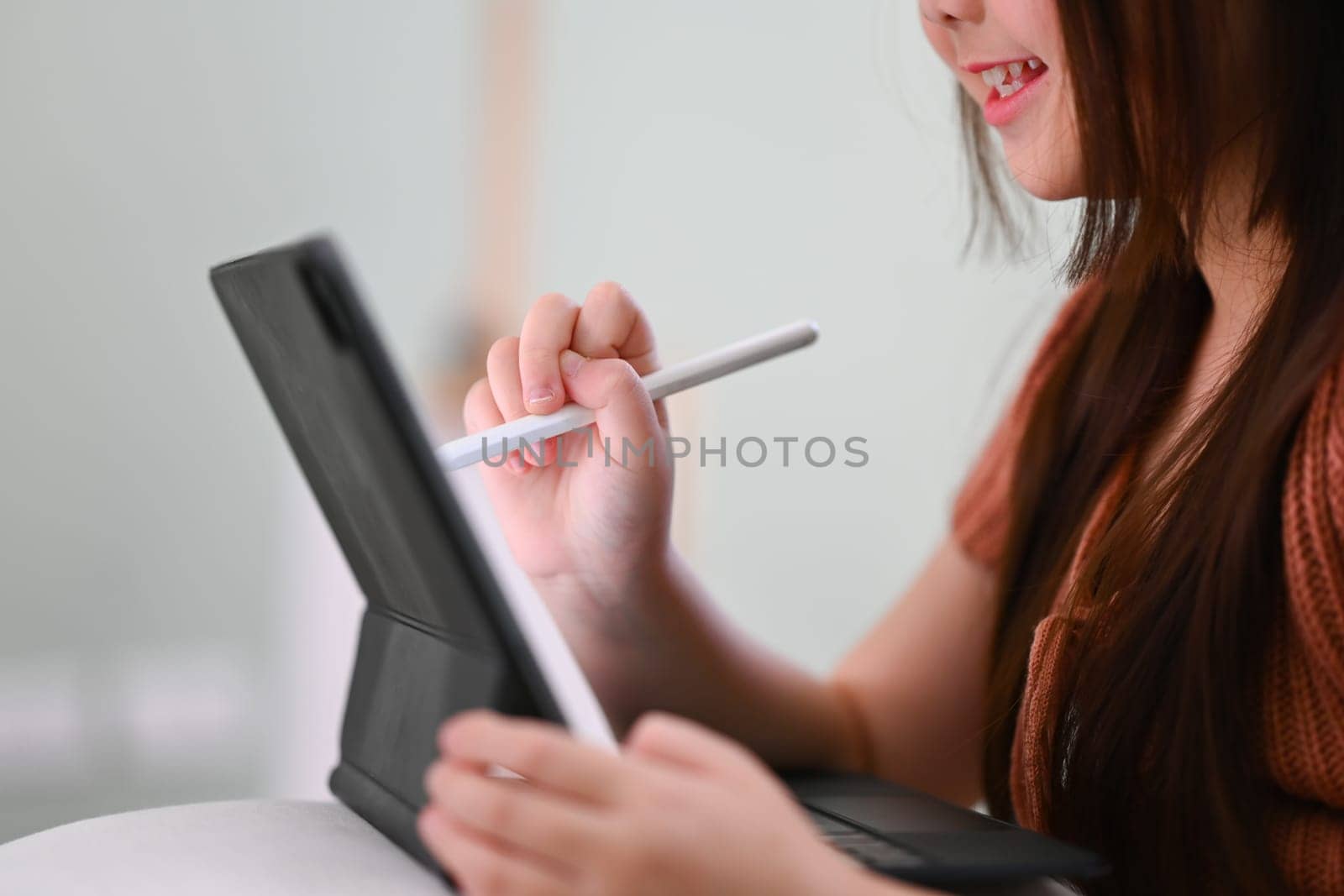 Shot of asian girl doing a school assignment on digital tablet at home. by prathanchorruangsak