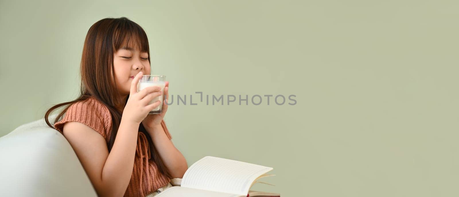 Little cute girl sitting drinking fresh milk in the morning. Calcium source and nutritional value concept