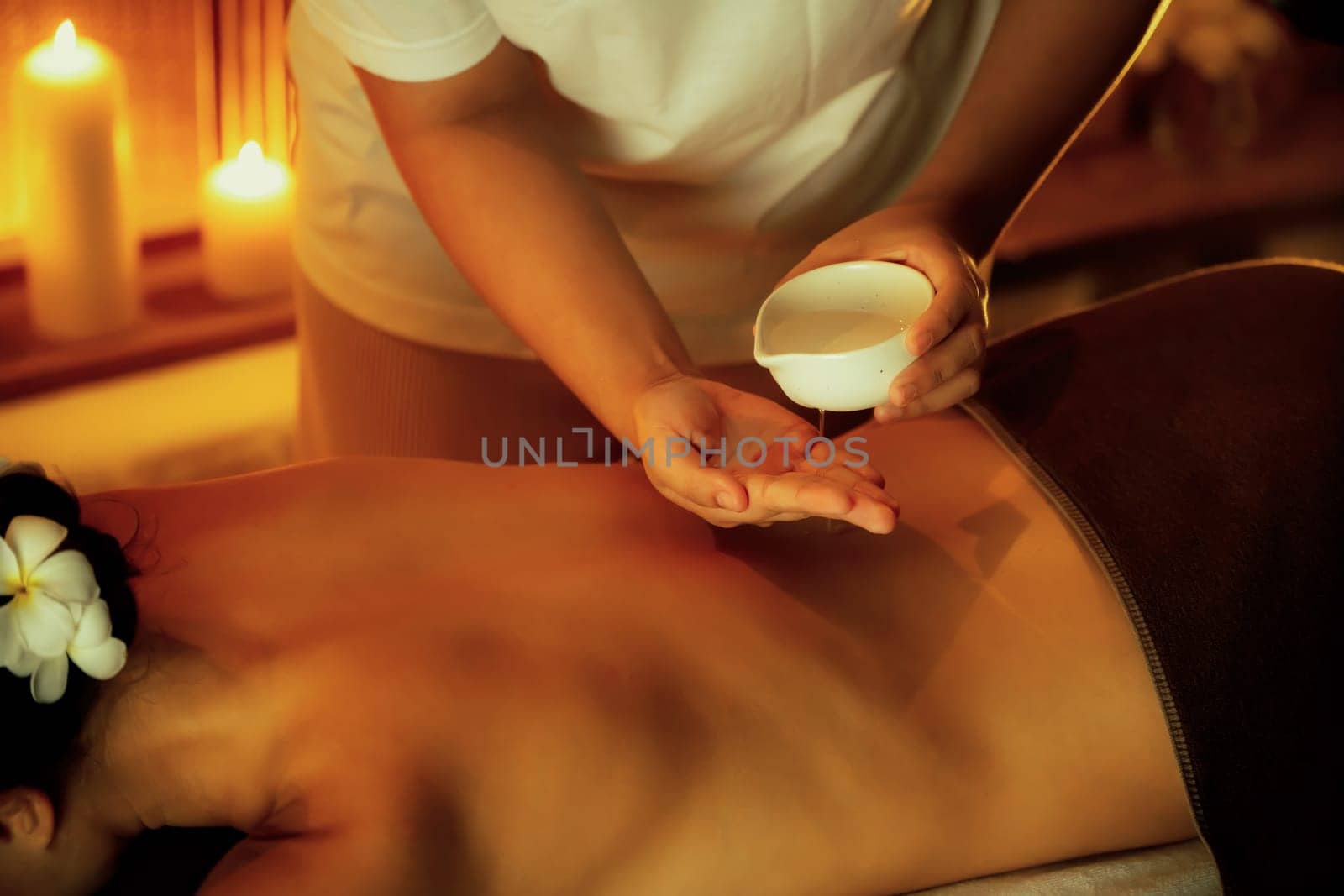 Masseur hands pouring aroma oil on woman back. Masseuse prepare oil massage procedure for customer at spa salon in luxury resort. Aroma oil body massage therapy concept. Quiescent