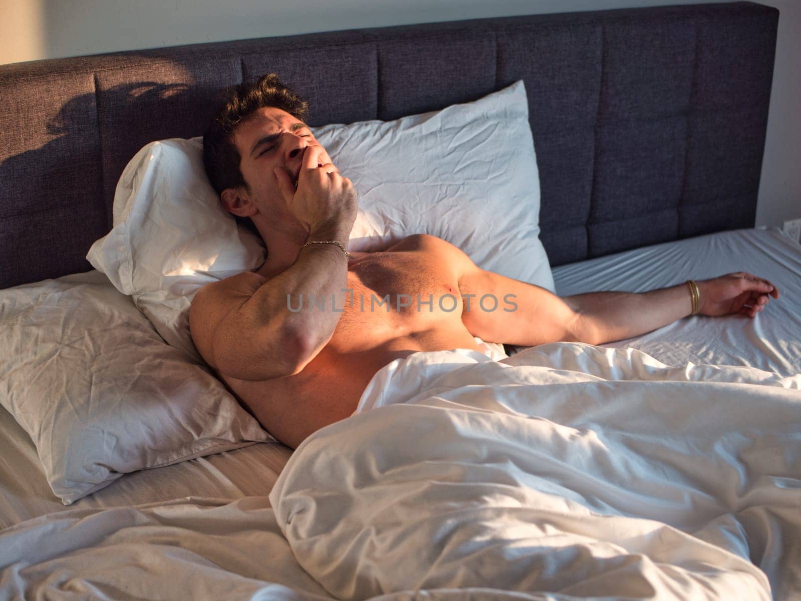 Photo of a shirtless man relaxing on a bed with crisp white sheets by artofphoto