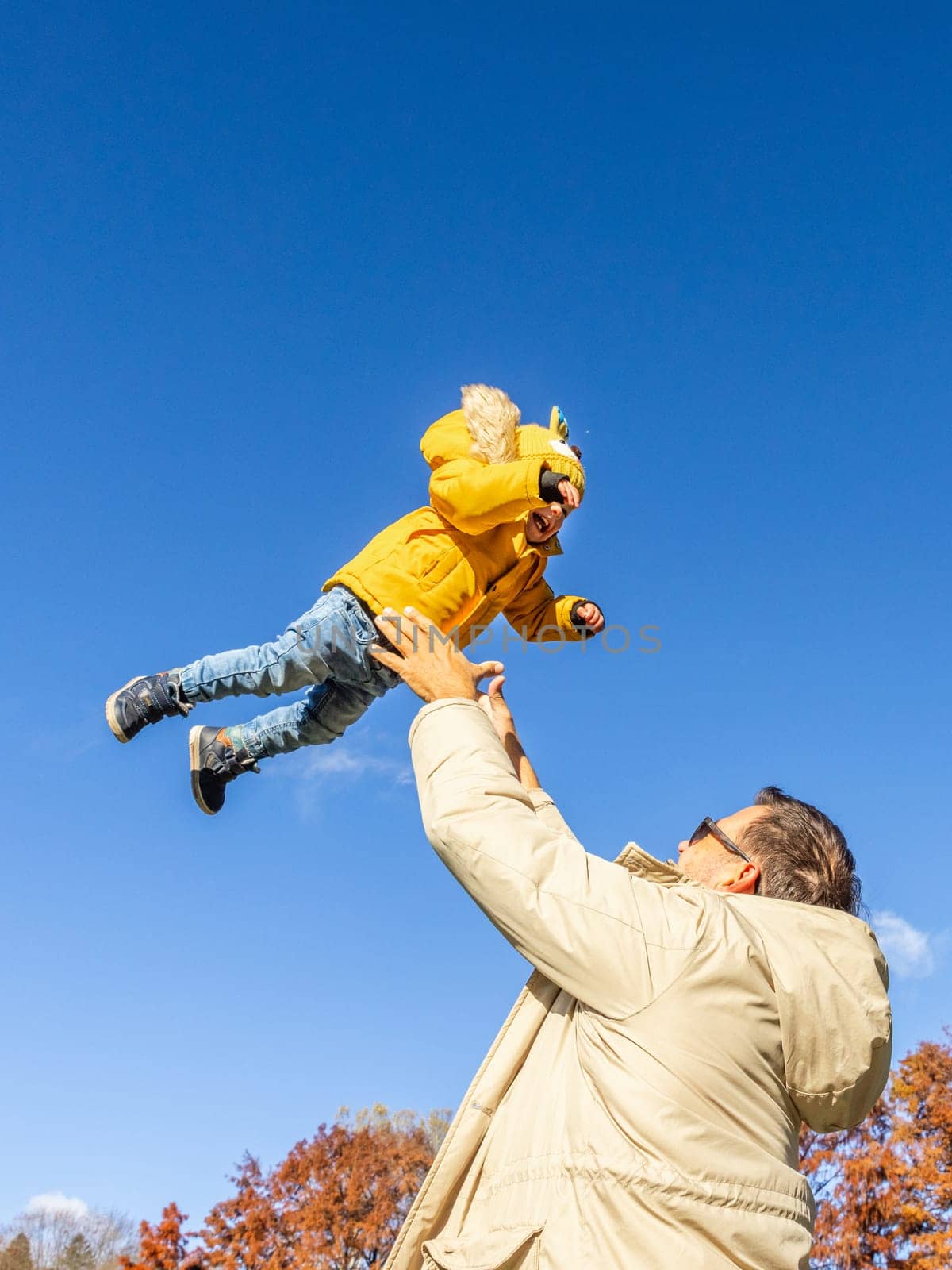 More, more,... dad, that's fun. Happy young father throws his cute little baby boy up in the air. Father's Day, Father and his son baby boy playing and hugging outdoors in nature in fall