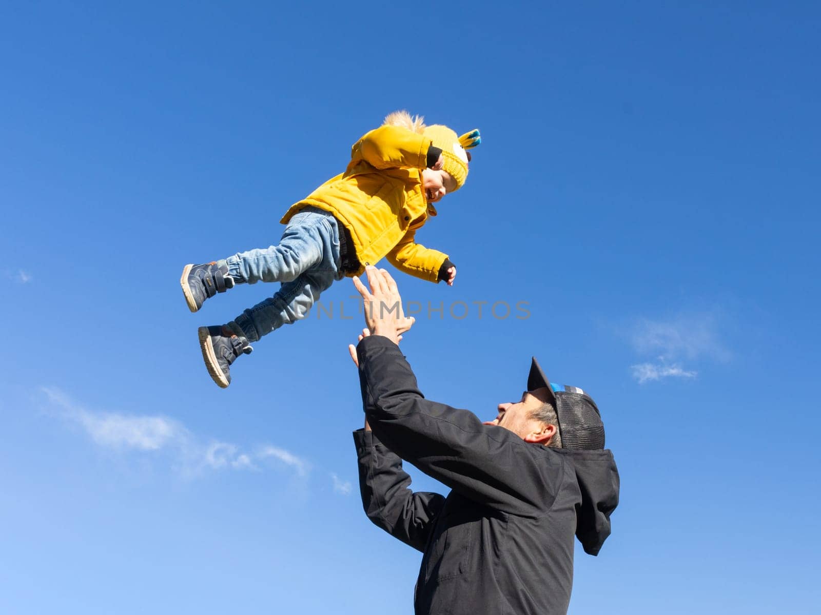 More, more,...dad, that's fun. Happy young father throws his cute little baby boy up in the air. Father's Day, Father and his son baby boy playing and hugging outdoors in nature in fall. by kasto