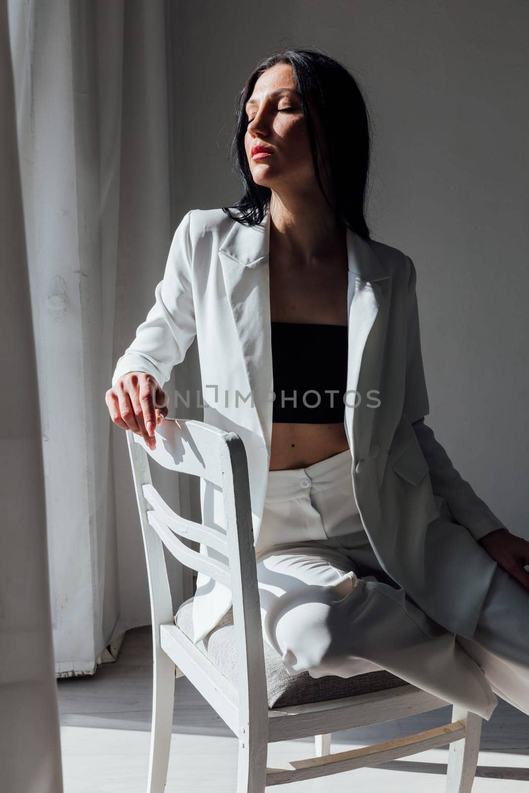 fashionable slender brunette woman sitting on a chair