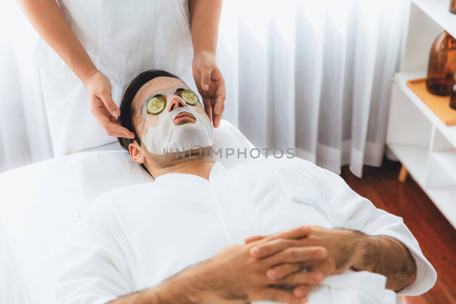 Man customer indulges in rejuvenating with cucumber facial care. Quiescent by biancoblue