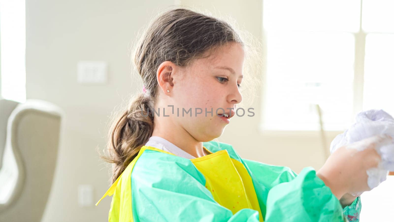 In a modern kitchen, a homeschooled girl is engrossed in creating homemade slime, a fun and educational hands-on project that enhances her creativity and problem-solving skills.