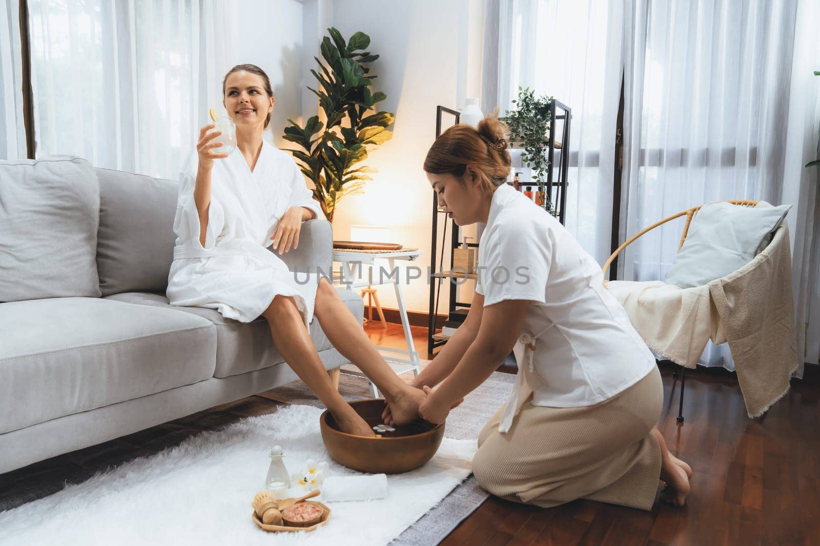 Woman indulges in blissful foot massage at luxurious spa salon while masseur give reflexology therapy in gentle day light ambiance resort or hotel foot spa. Quiescent