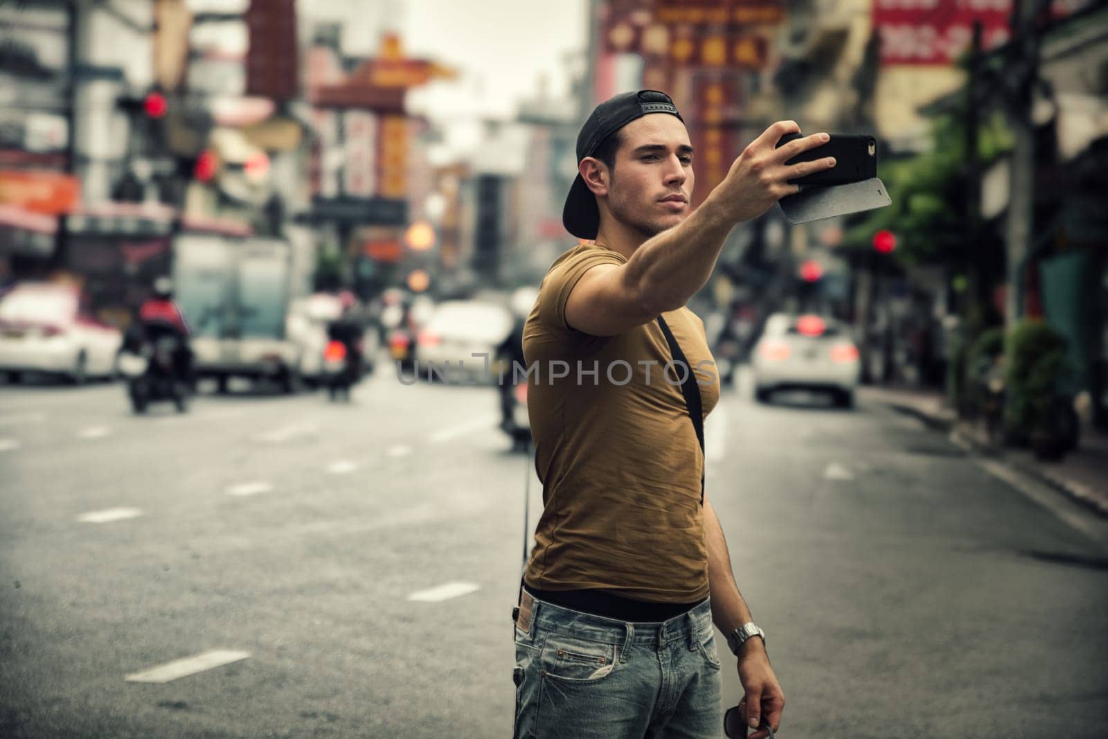 A man taking a selfie on a busy city street. Photo of a man capturing a selfie amidst the vibrant hustle and bustle of a bustling city street in Thailand