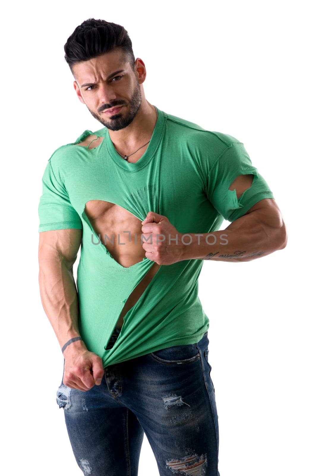 Attractive muscular strong man in ripped t shirt, isolated on white background in studio, looking at camera