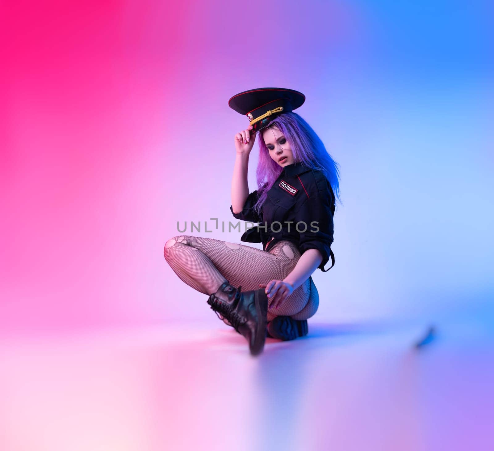 Sexy girl in police military uniform posing in lingerie with a police rubber baton in neon light by Rotozey