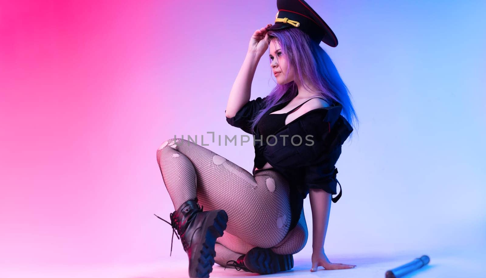 Sexy girl in police military uniform posing in lingerie with a police rubber baton in neon light by Rotozey