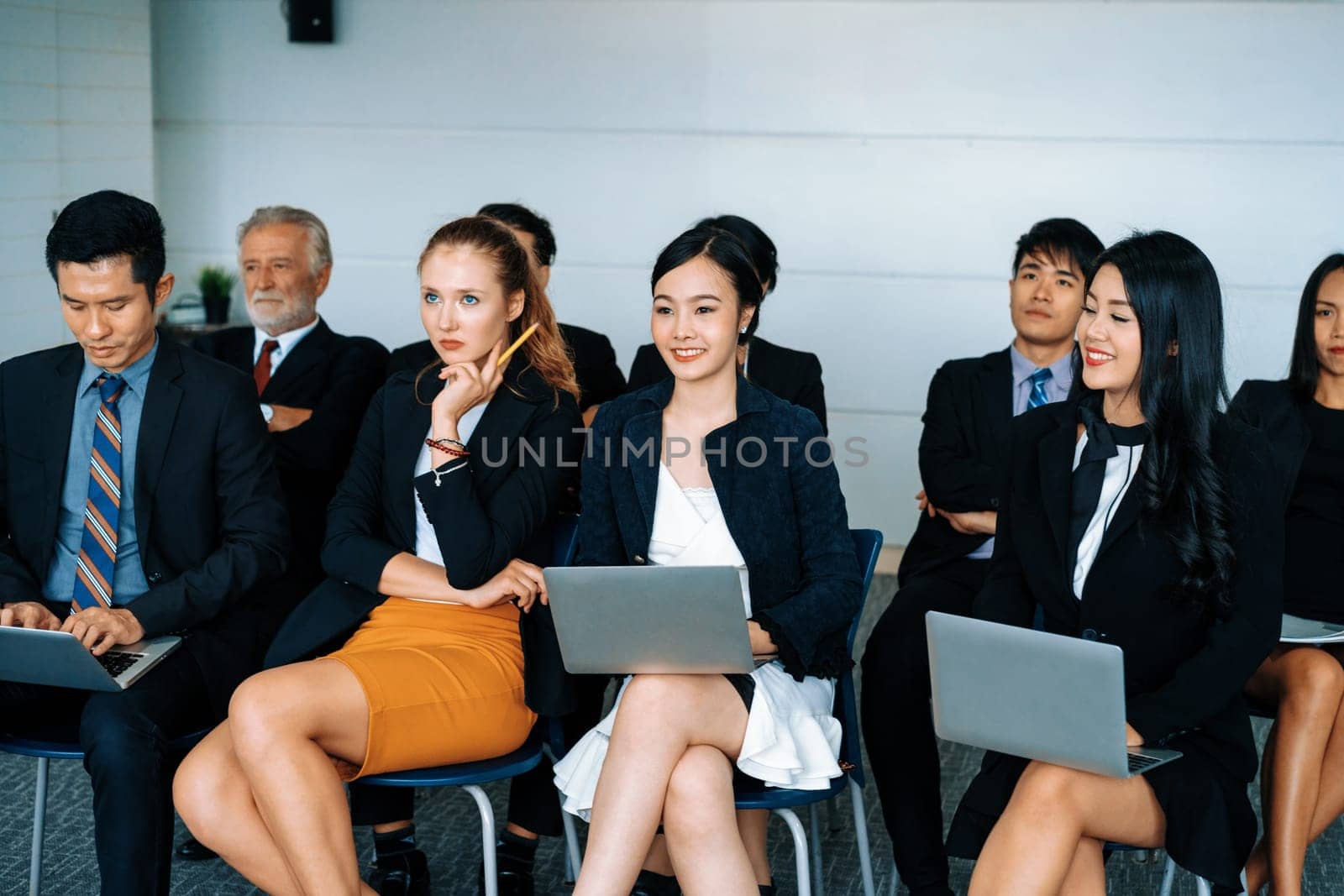 Young Asian and Caucasian audience sitting and listen to speaker in group meeting presentation at office. Businessmen and businesswomen in training workshop. International multicultural business. uds