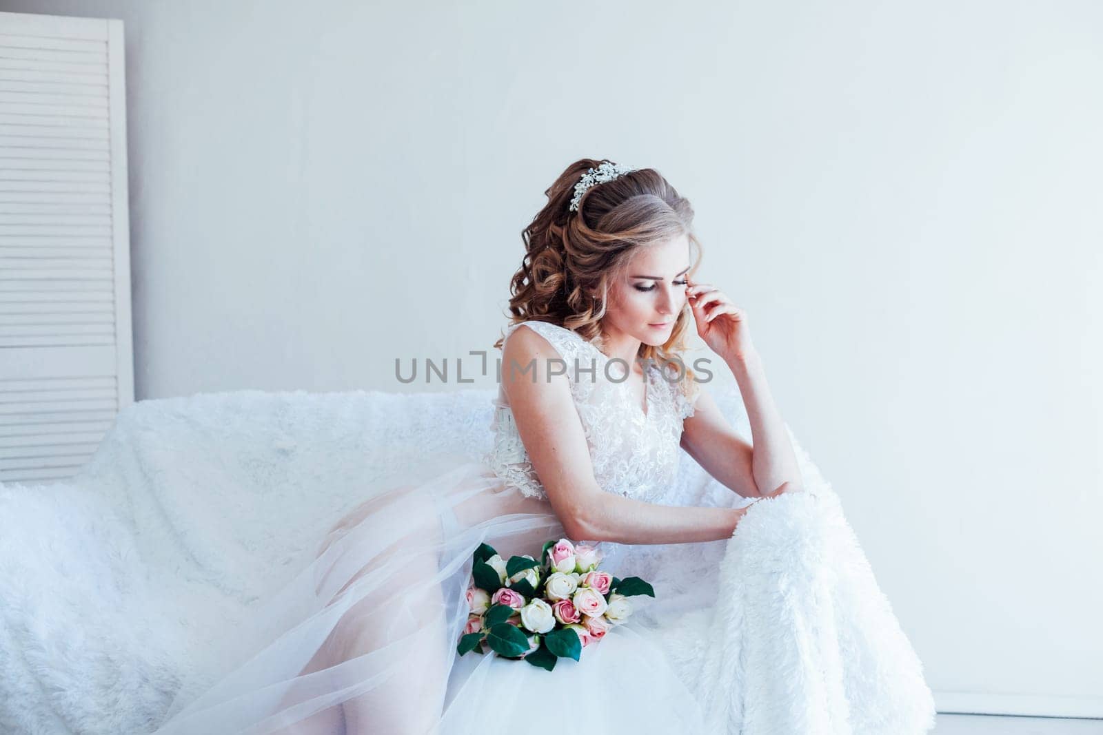 beautiful bride sitting on a white couch in lingerie by Simakov