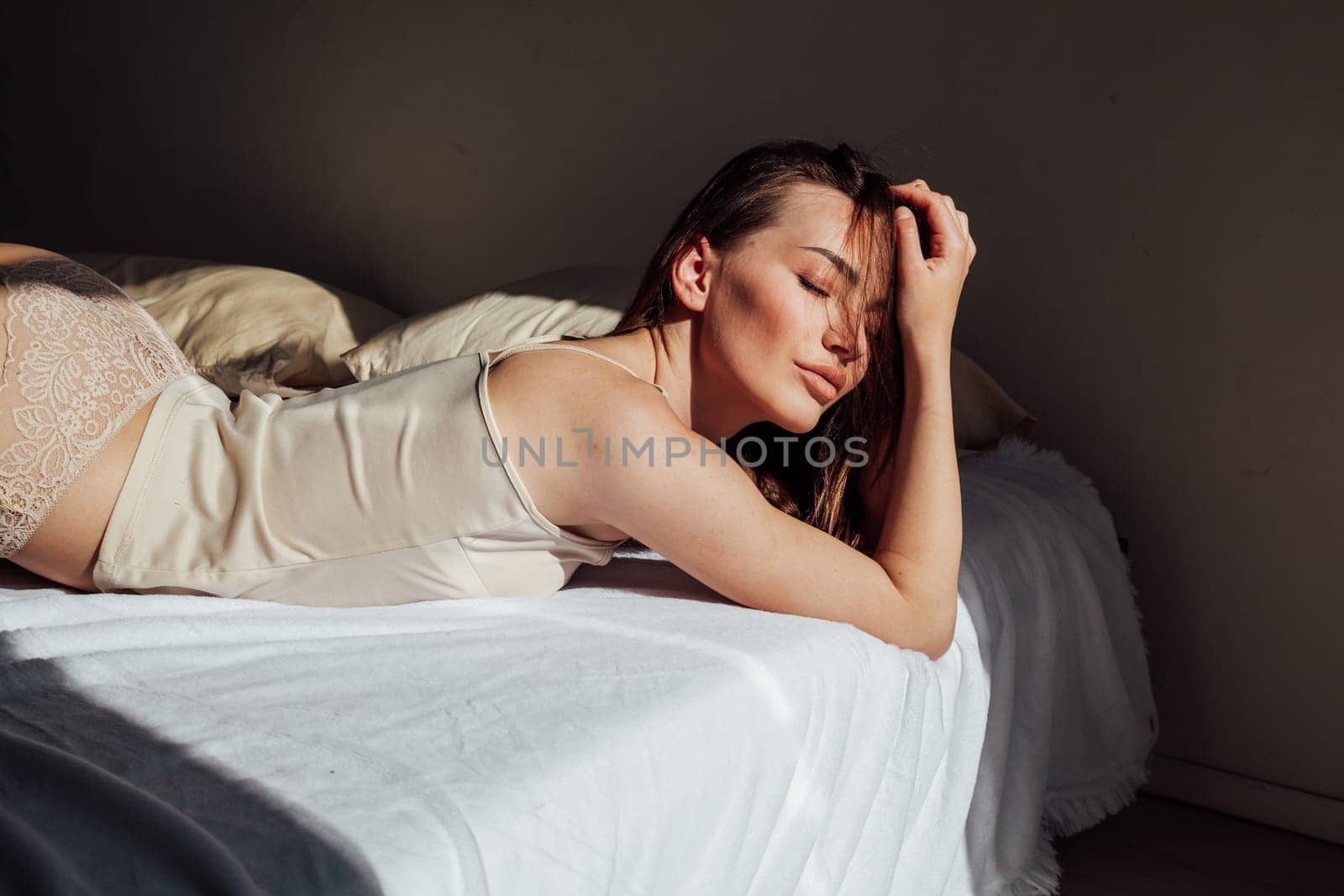 brunette woman in gray underwear lies on the bed in the bedroom by Simakov