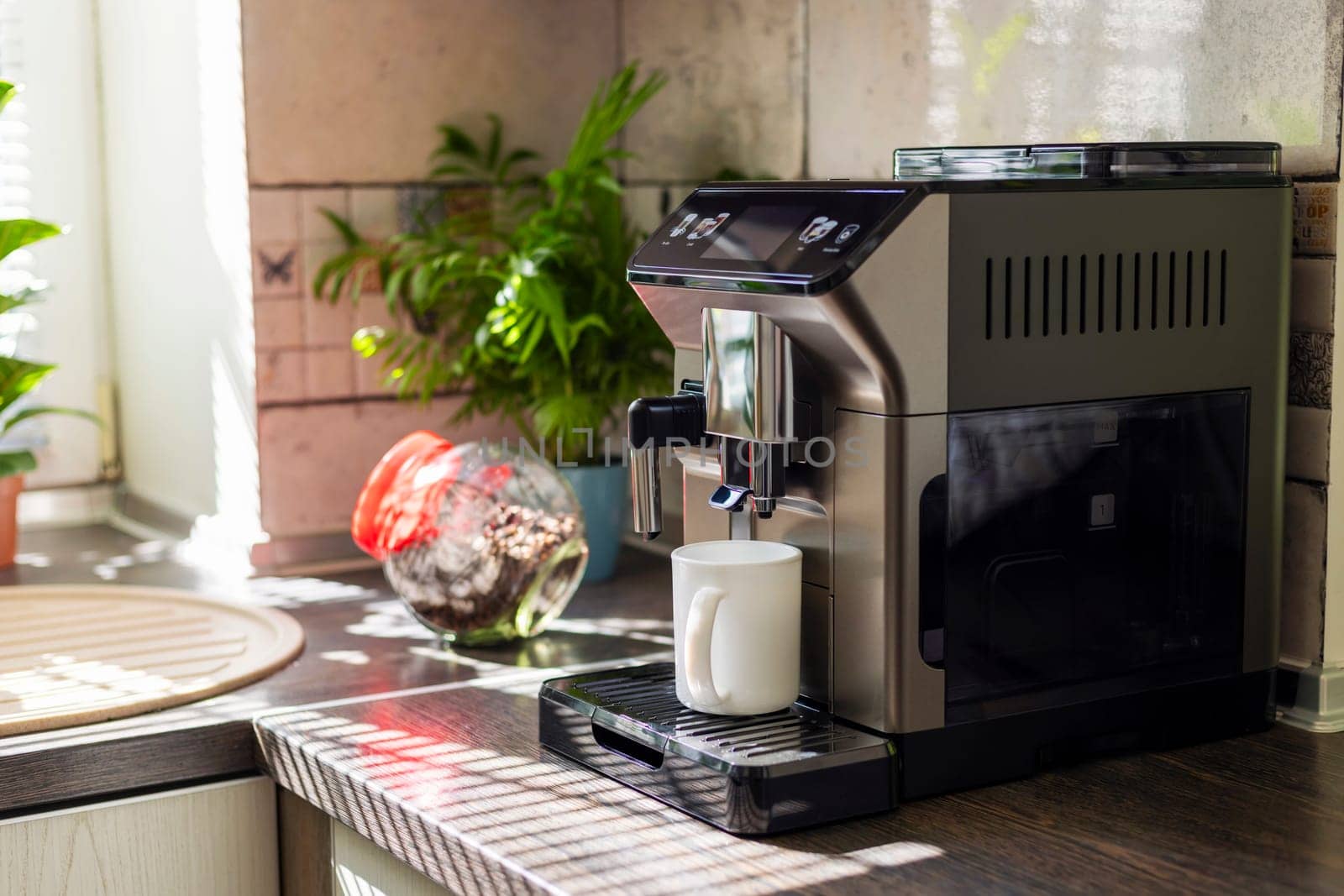 Modern electric coffee machine with cup on countertop in kitchen by andreyz